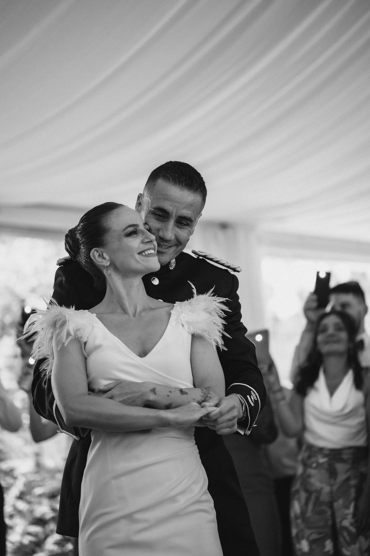A couple shares a joyful dance moment at their wedding reception, spinning and laughing under a white tent.