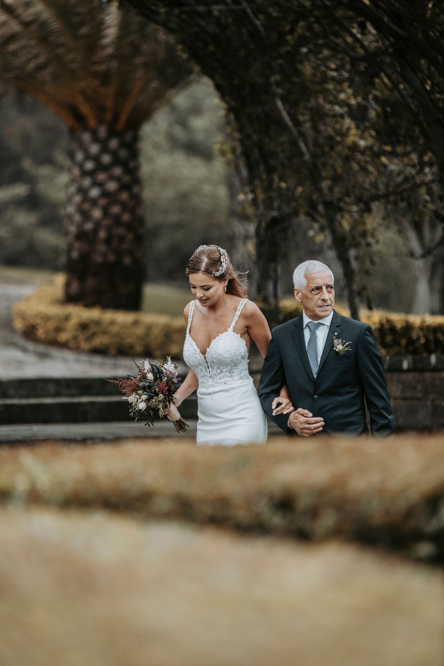 A tender moment captured between a bride in a white dress and her companion during an outdoor wedding ceremony.