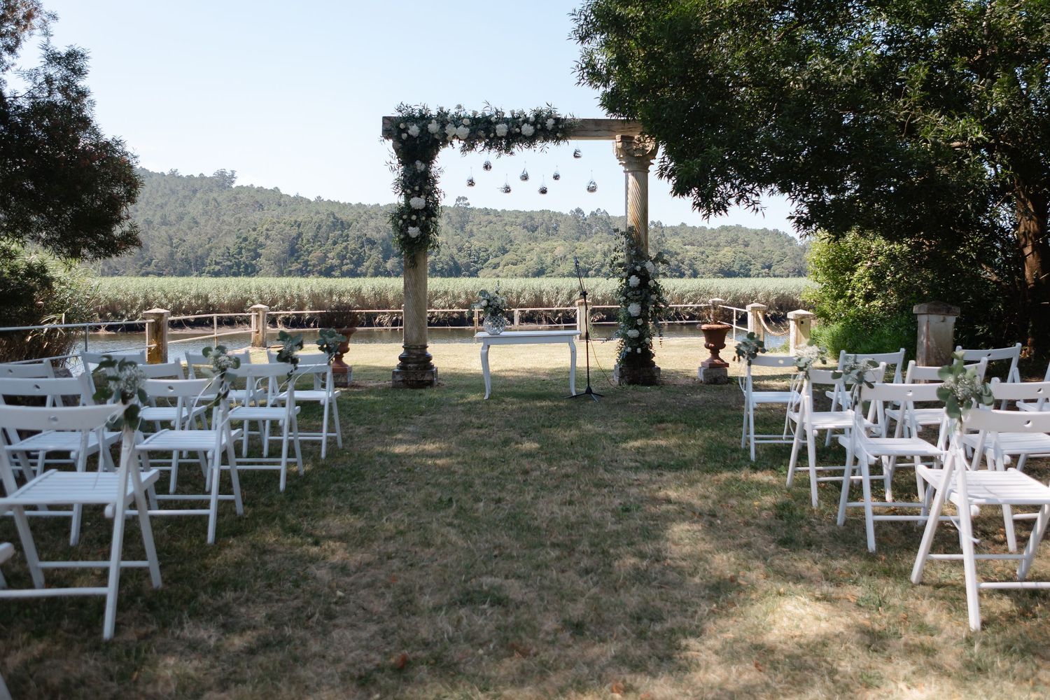 White wooden chairs arranged outdoors for a rustic wedding ceremony with mountain views in the background.