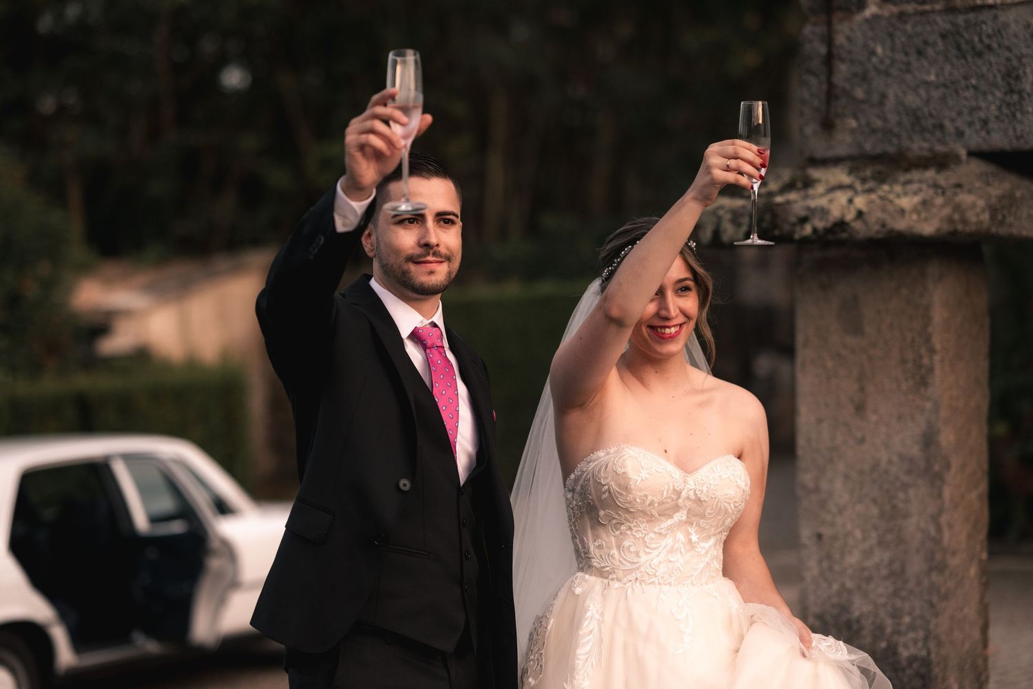 A couple raises their glasses in celebration during their wedding ceremony outdoors.