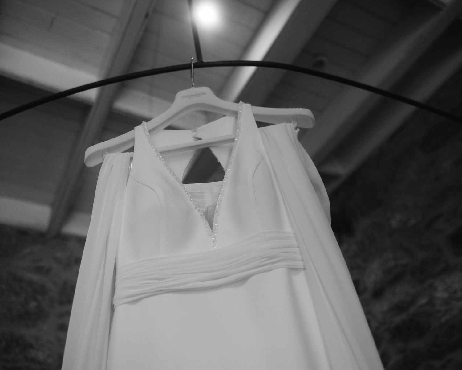 White wedding dress hanging on display against a dark background with dramatic lighting.