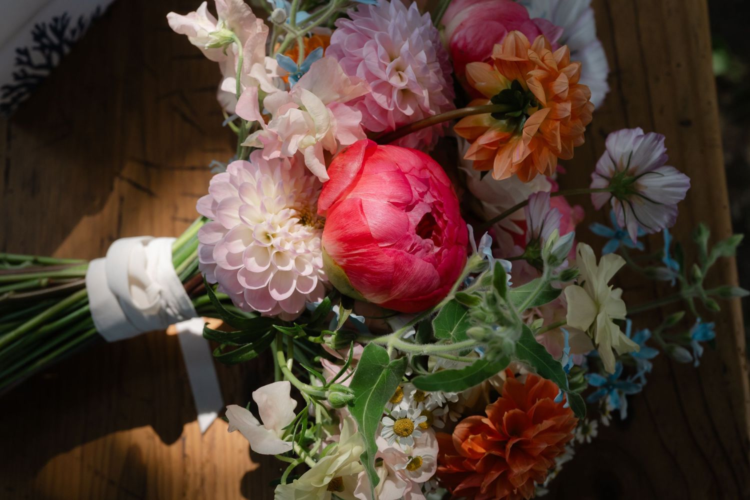 A romantic arrangement of pink and coral flowers with peonies and roses in soft natural light.