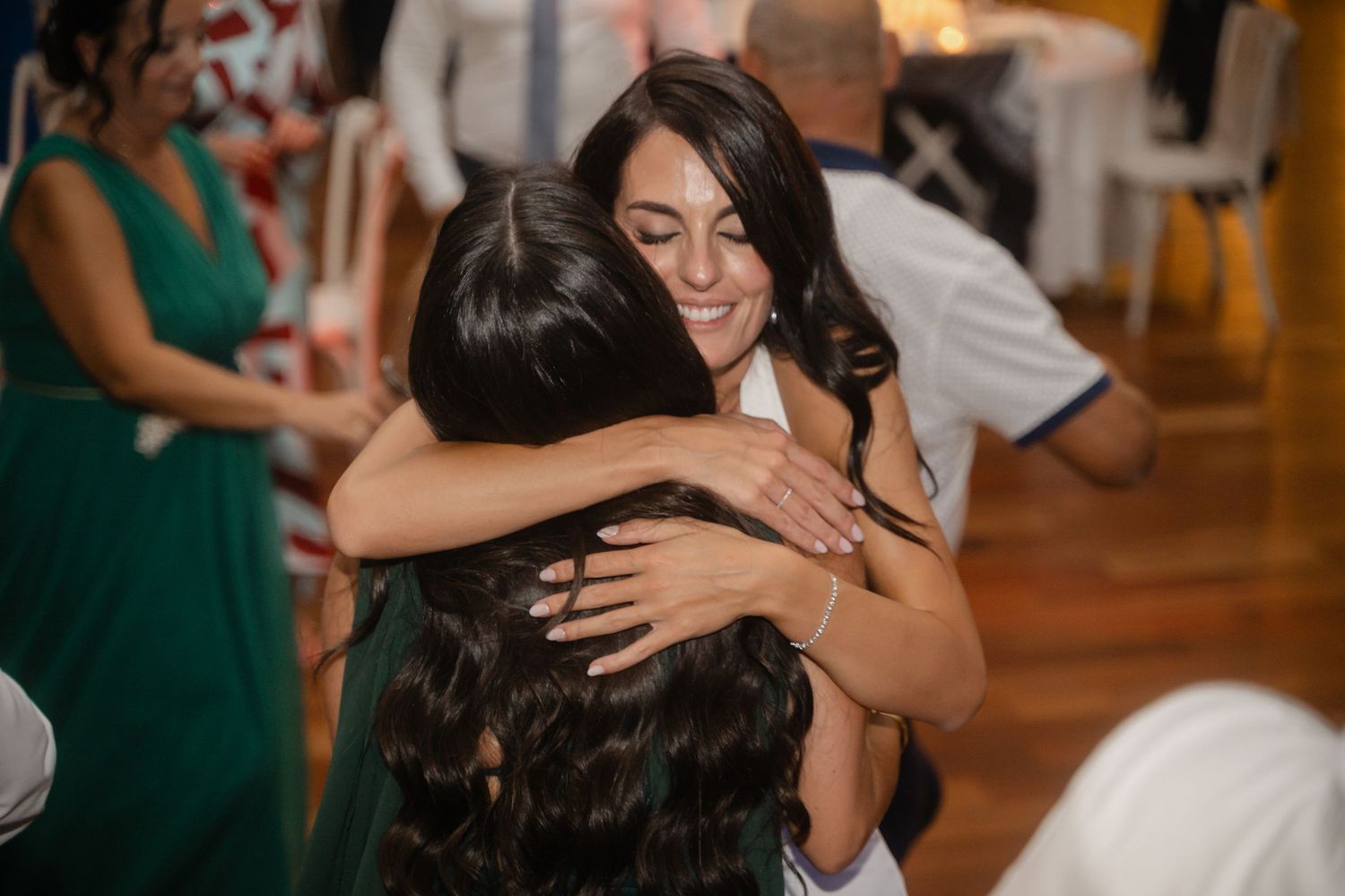 Couples dancing together at an elegant wedding reception with hardwood floors and ambient lighting.