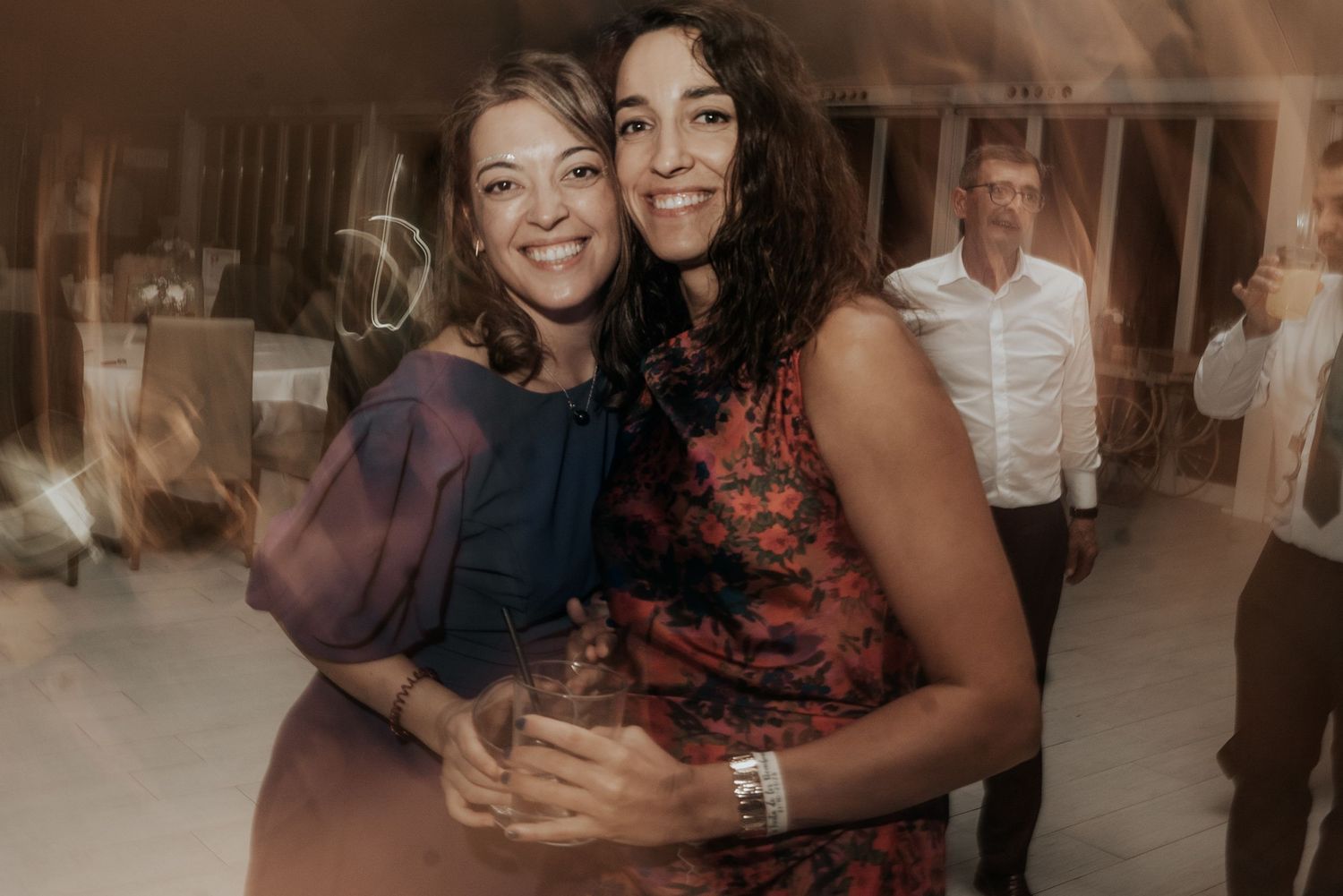 People celebrating and dancing together at a wedding reception in a rustic venue with warm lighting.