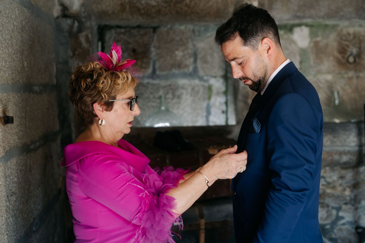 A couple dancing together in a rustic stone room, with the woman wearing a vibrant pink dress.