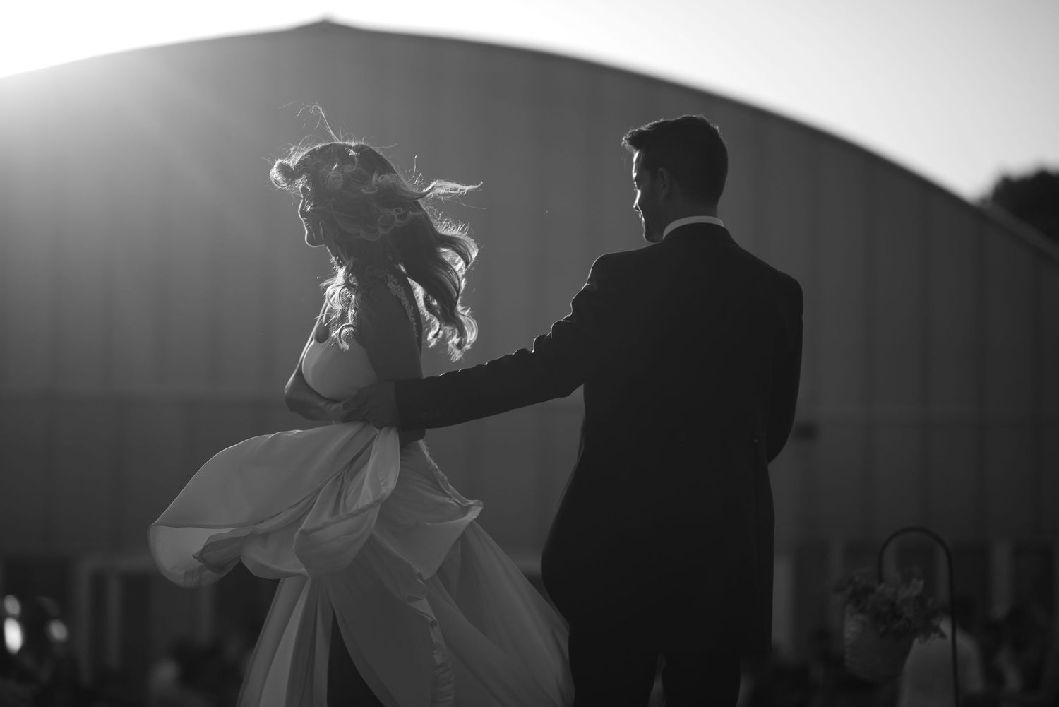 Dramatic black and white silhouettes of a couple dancing at their wedding reception.