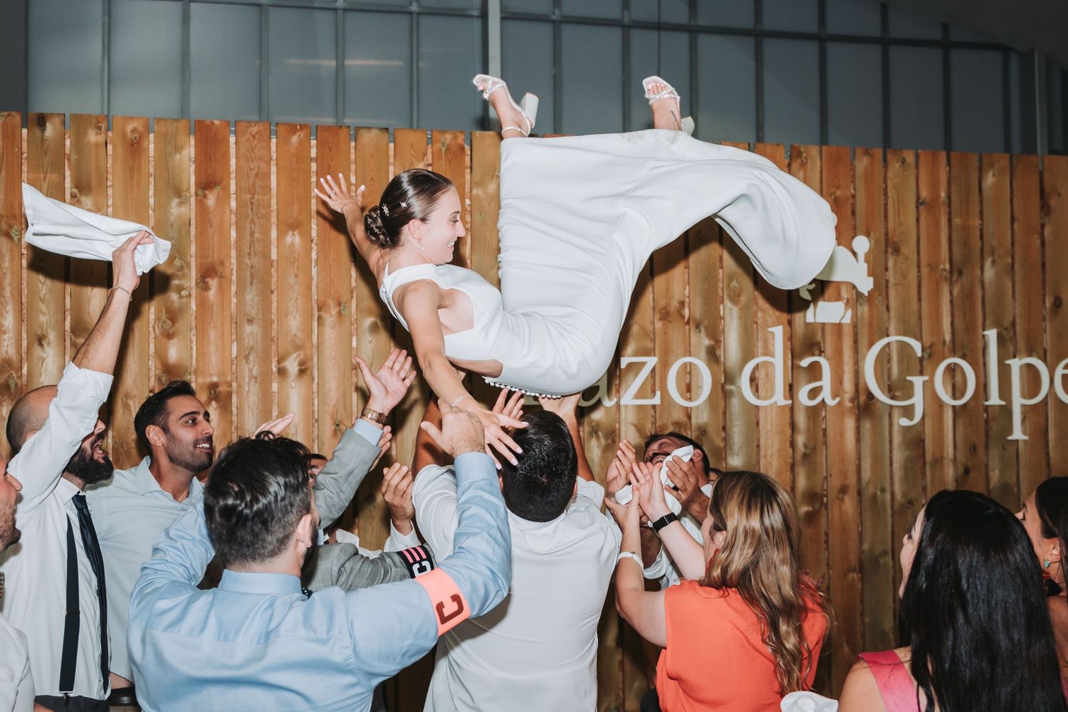 Wedding guests dance and celebrate together on a dance floor at an indoor reception venue.