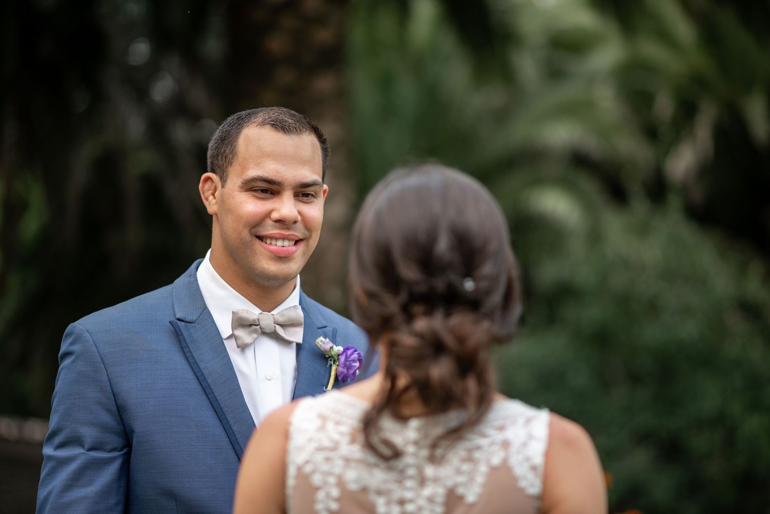 A couple in wedding attire shares a romantic moment together in an outdoor garden setting.