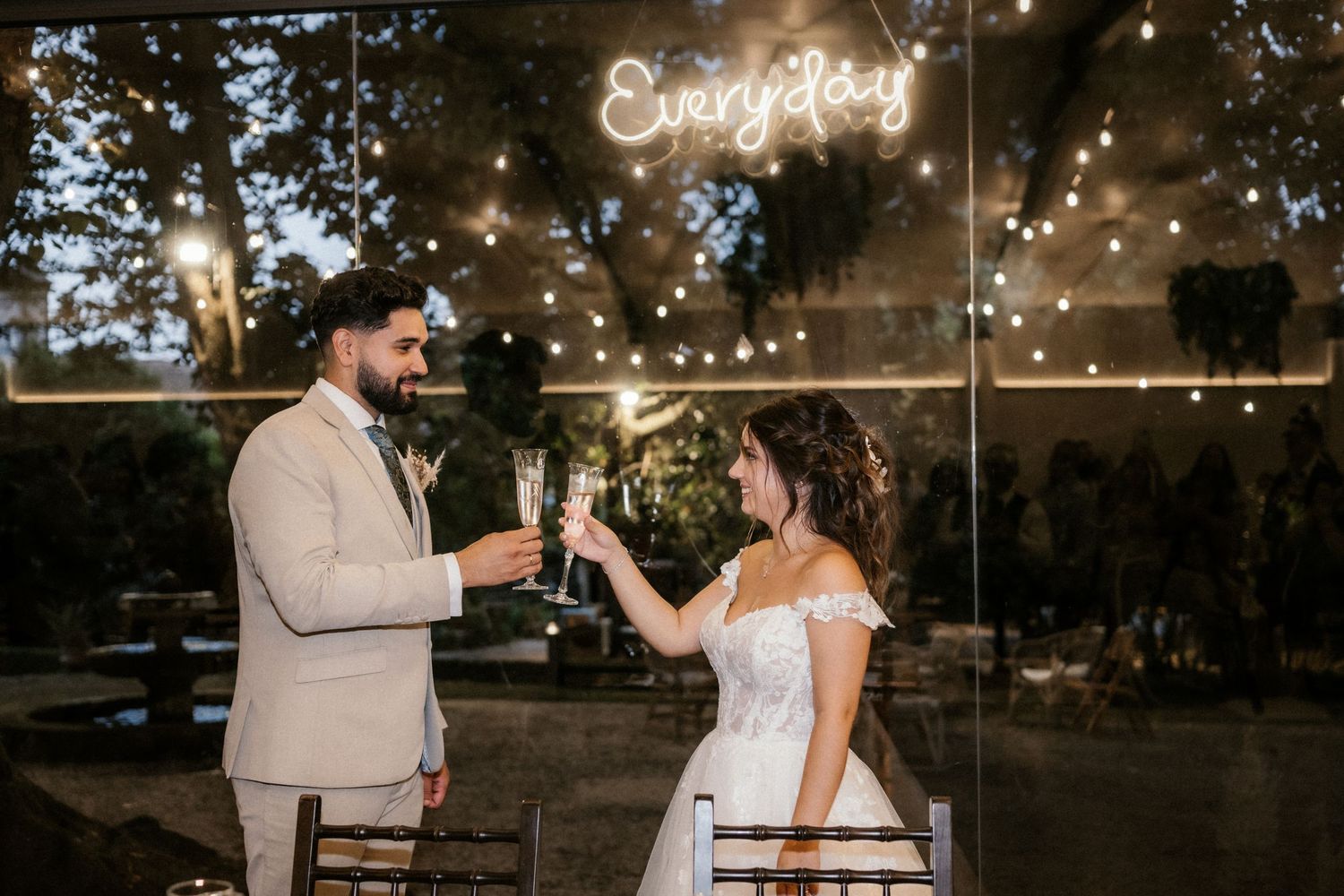 Wedding couple shares a toast during golden hour at an outdoor reception celebration.