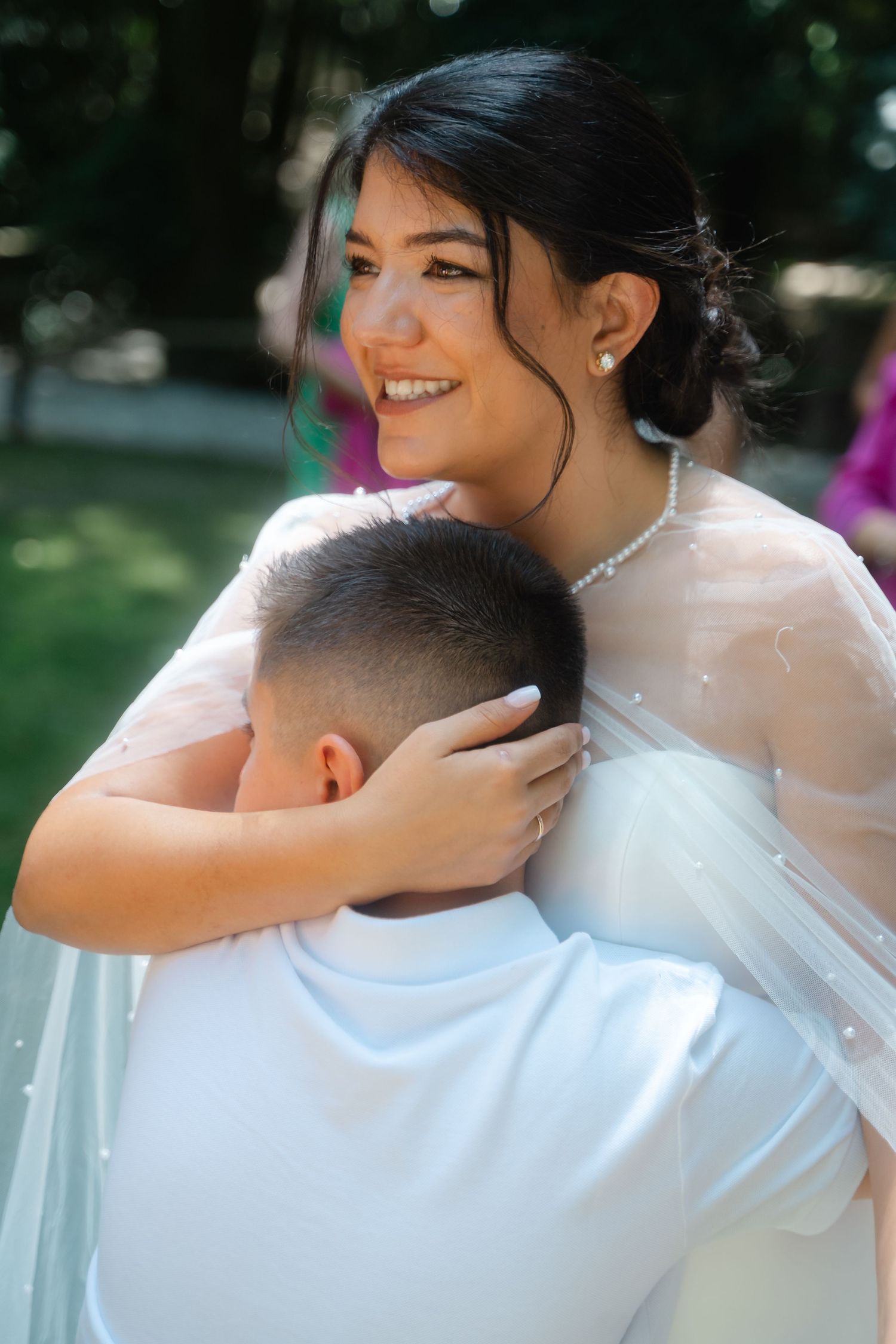Intimate wedding couple embraces captured in soft natural light with delicate veil details.