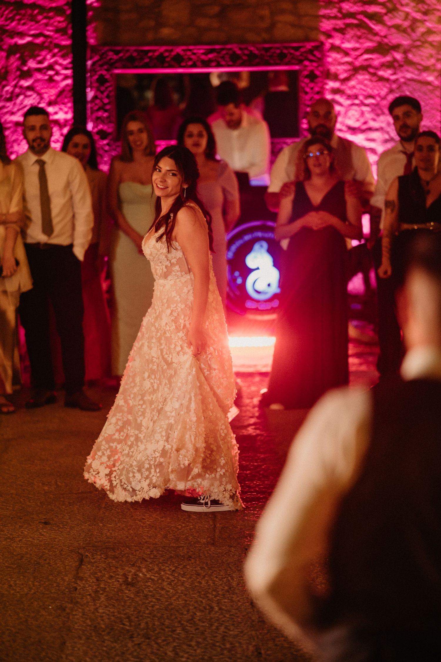 A sequence of dance moves in a wedding reception with pink lighting and a white lace dress.