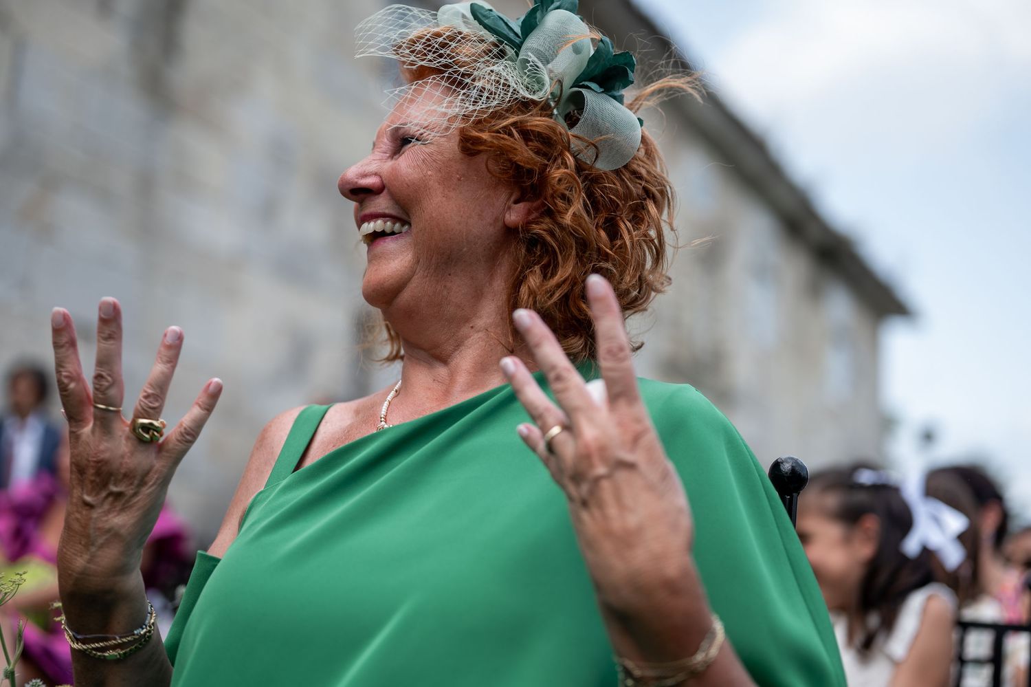 Two people wearing matching green shirts celebrate joyfully outdoors with raised hands and big smiles.
