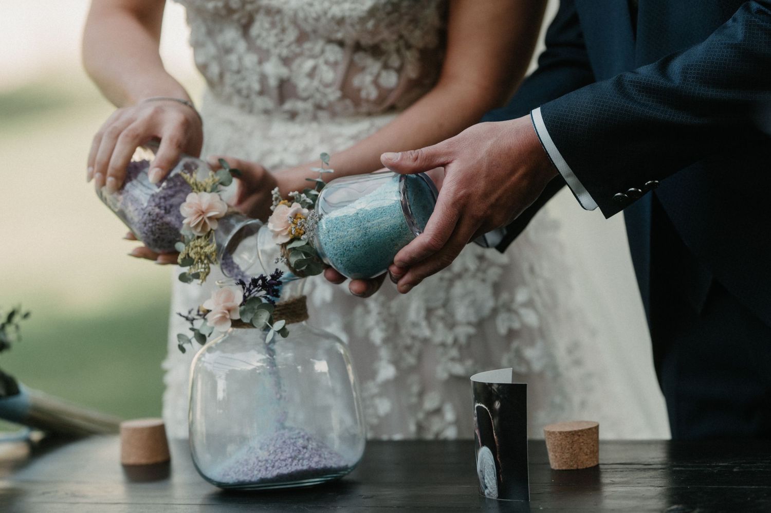 Close-up view of hands holding a white beaded bridal clutch purse at an outdoor wedding.