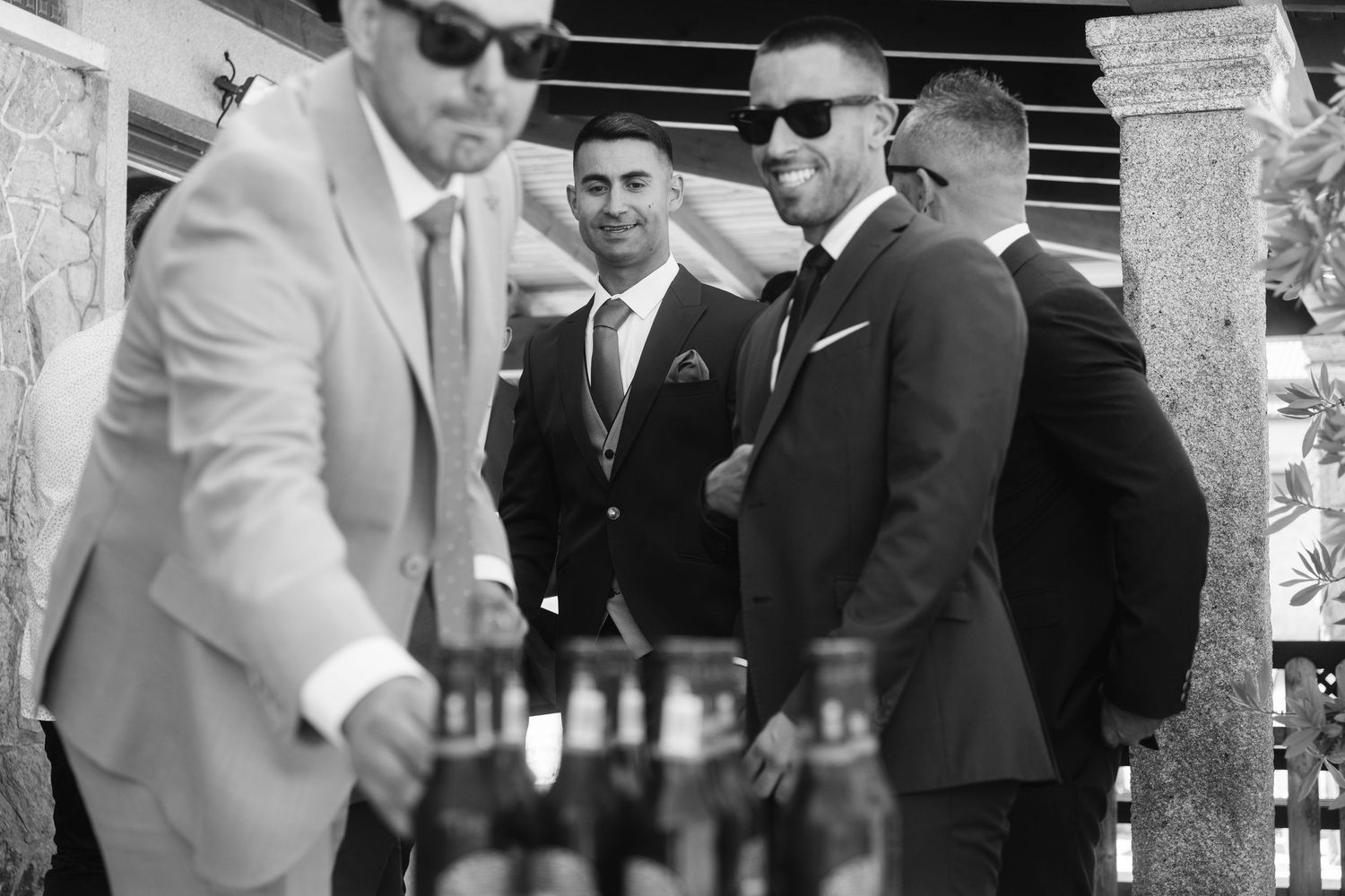 Group of groomsmen in formal attire gathered together at outdoor venue.