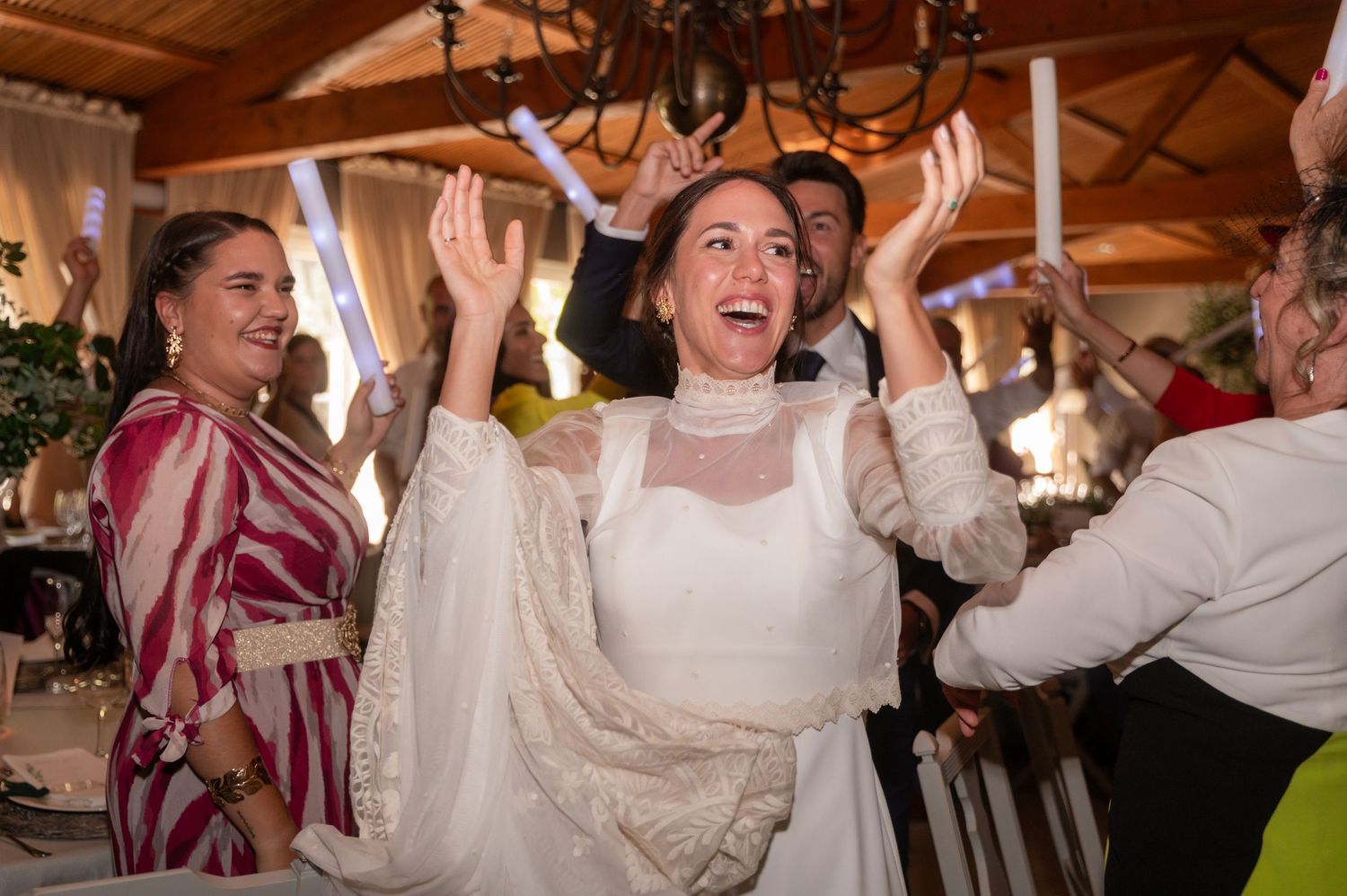 Guests laugh and dance enthusiastically during a lively wedding reception celebration.