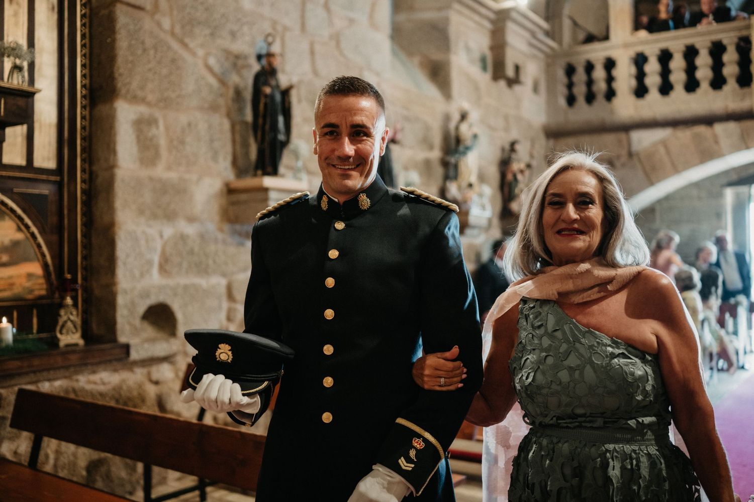 Wedding party enjoys drinks and conversation in a rustic stone venue with elegant lighting and decor.