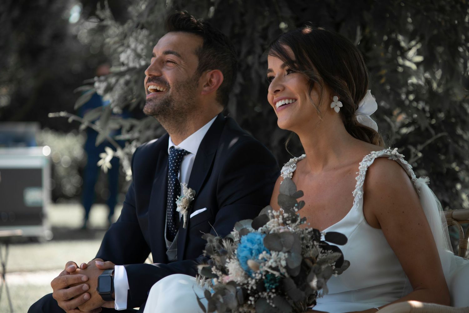 A newlywed couple shares a joyful moment while sitting together during their wedding celebration.