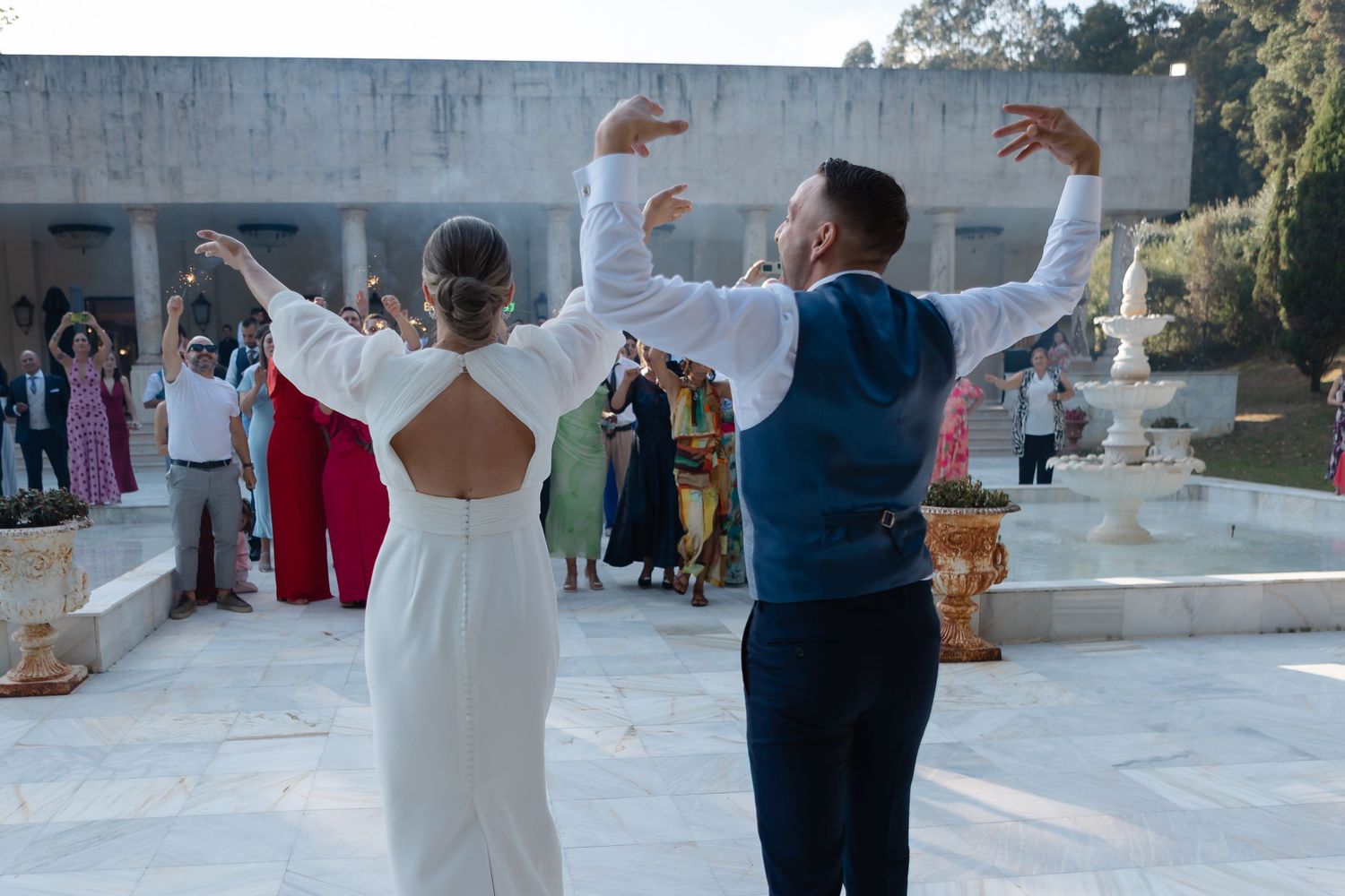 Couple performs their first dance at an outdoor wedding reception with guests watching in the background.