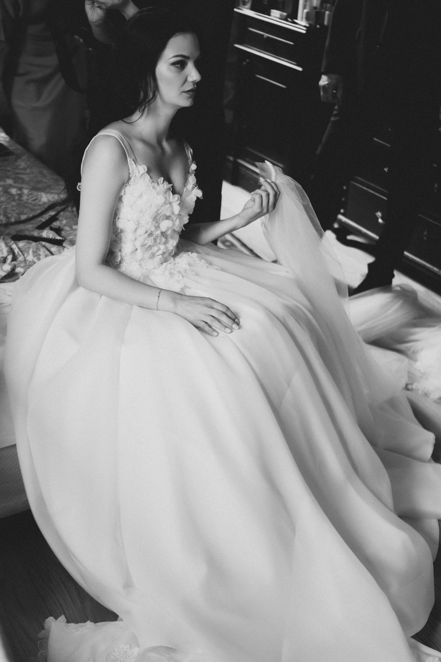 Dramatic black and white portrait of a wedding dress with delicate floral appliques and voluminous skirt.