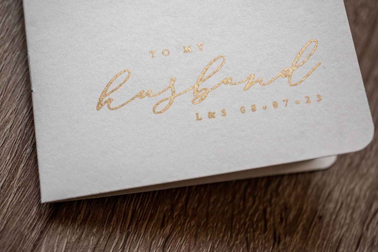 Gold foil calligraphy text details on white paper cards arranged on a wooden surface.