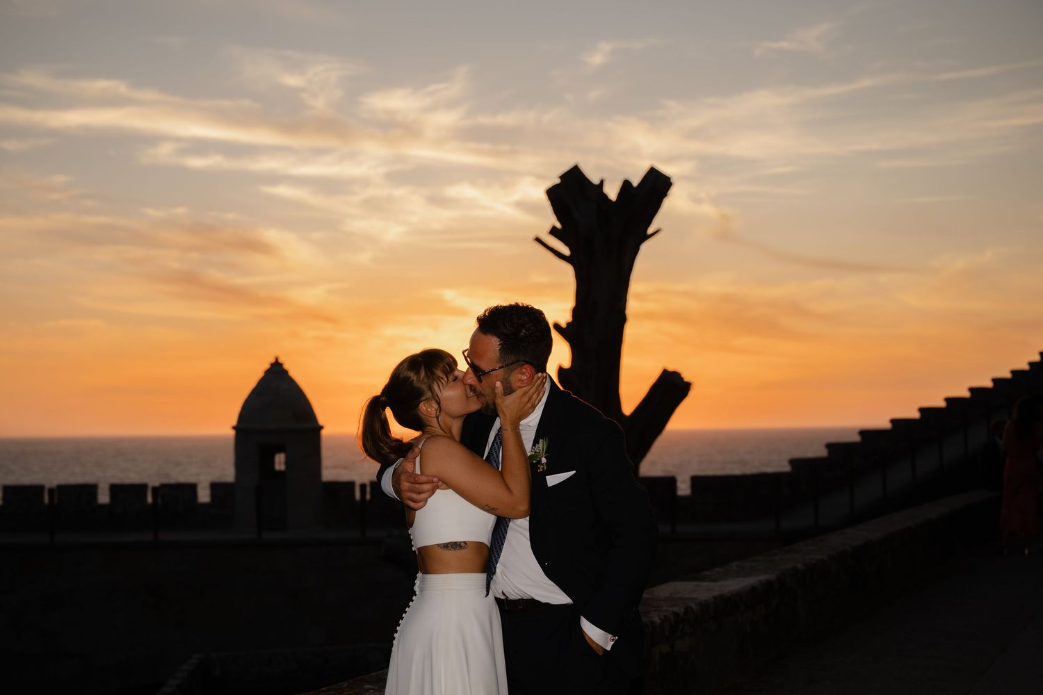 Romantic silhouettes of a couple embracing against a dramatic sunset sky.