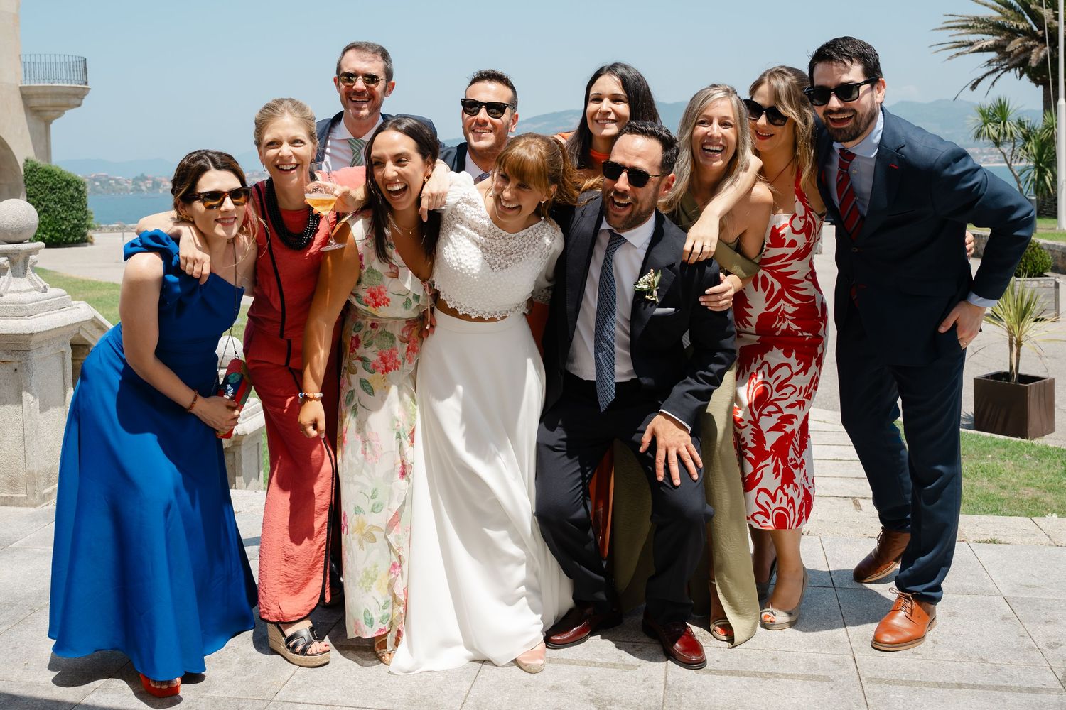 A group of wedding guests pose together outdoors in formal attire for a fun photo series.