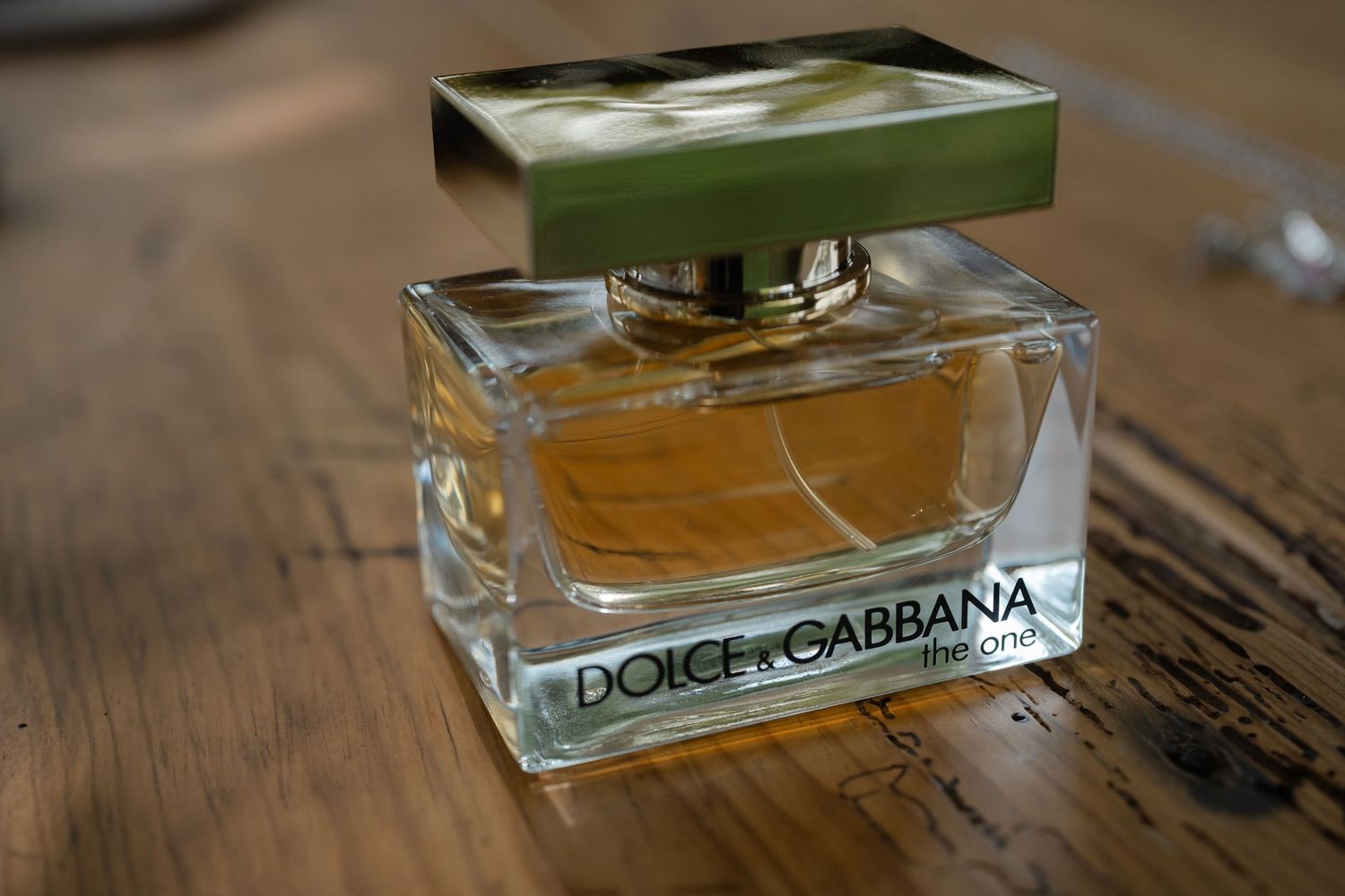 Row of elegant Dolce & Gabbana perfume bottles arranged on wooden surface with soft ambient lighting.