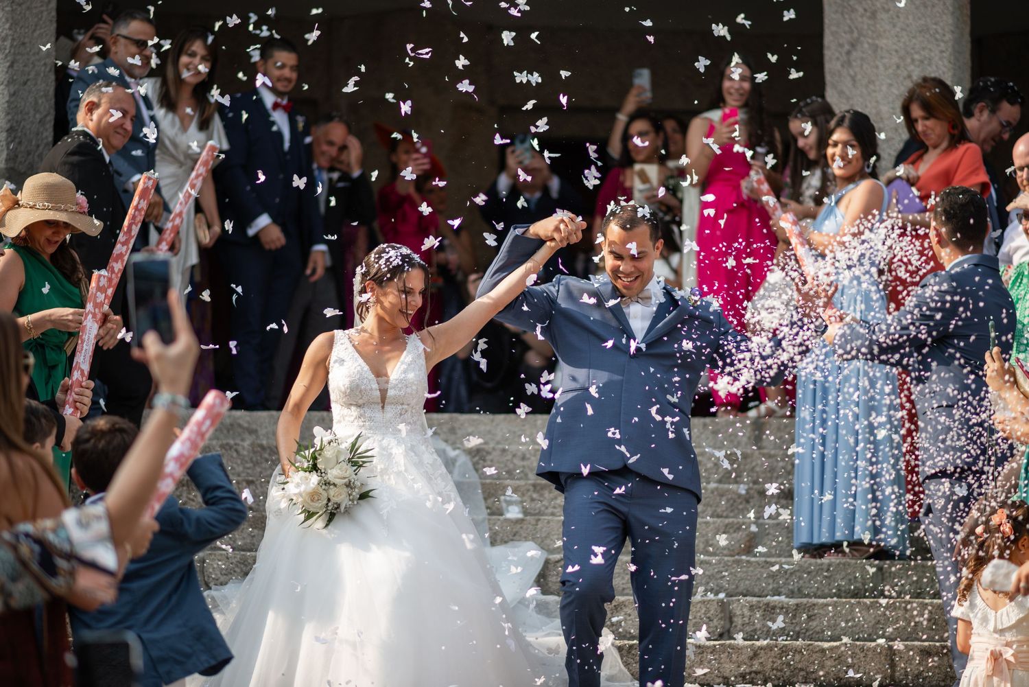 Wedding guests shower the newlyweds with confetti during a joyful outdoor celebration.