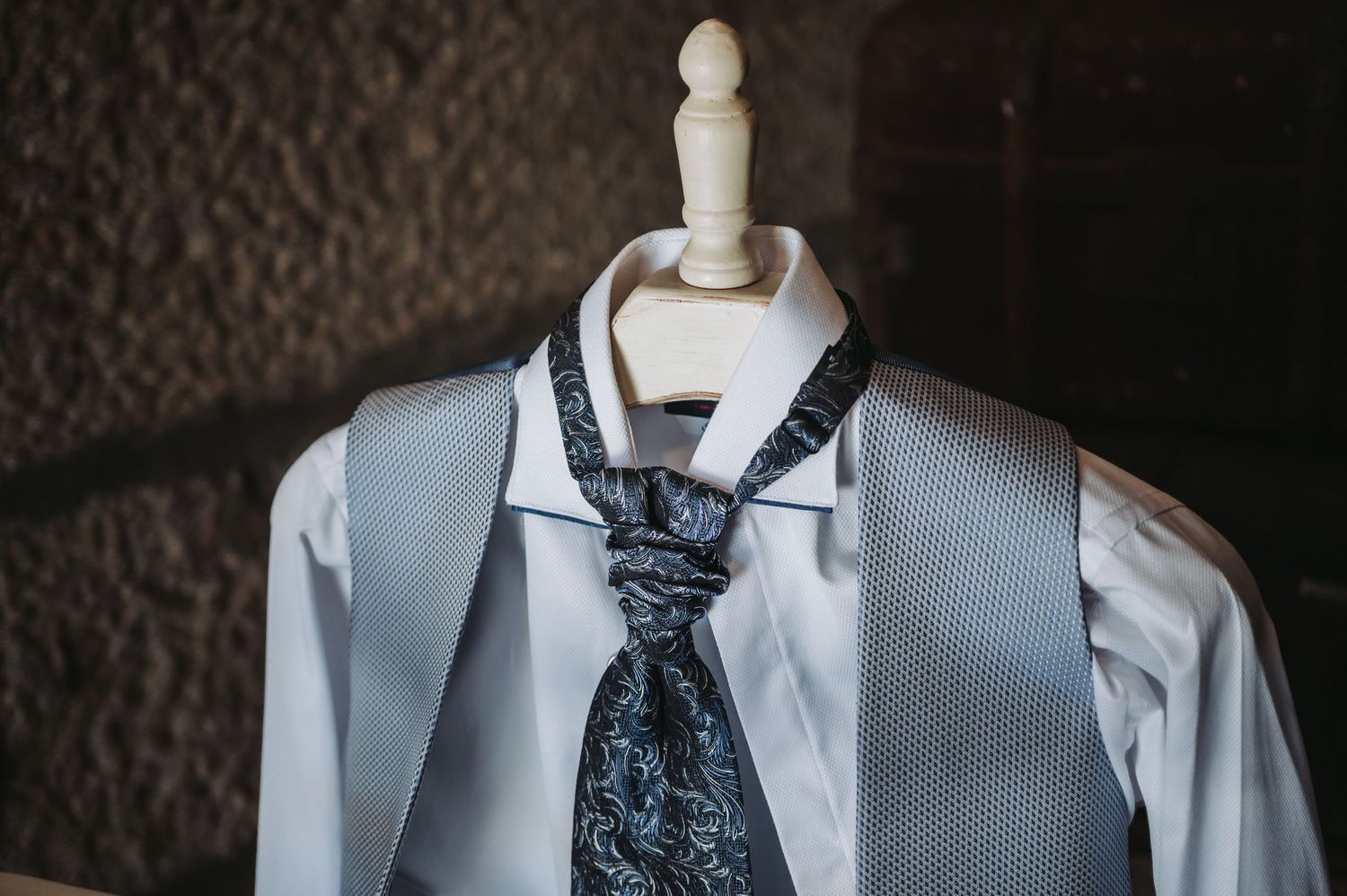 Detail shot of formal white dress shirts with navy blue ties arranged in a row.