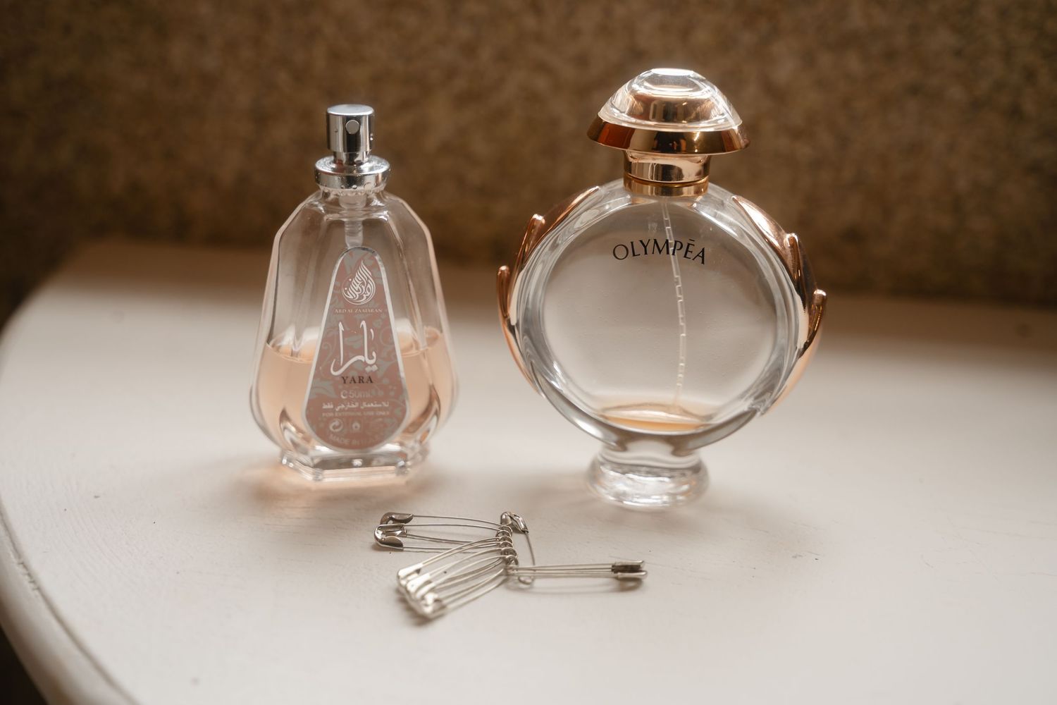 Elegant perfume bottles in a row displayed on a beige surface with soft lighting and blurred background effects.