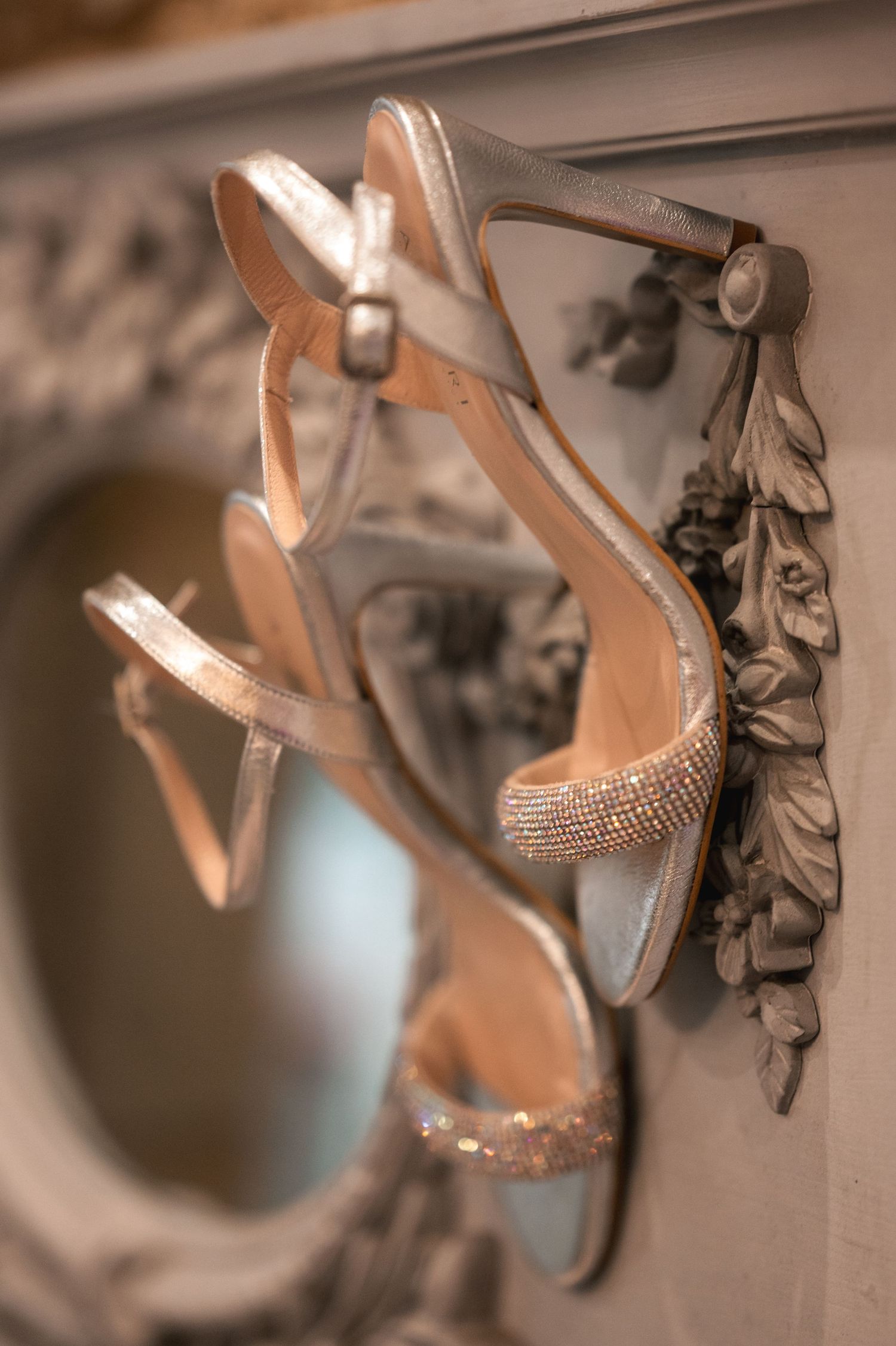 Elegant beige high heel sandals with rhinestone embellishments displayed against a blurred background.