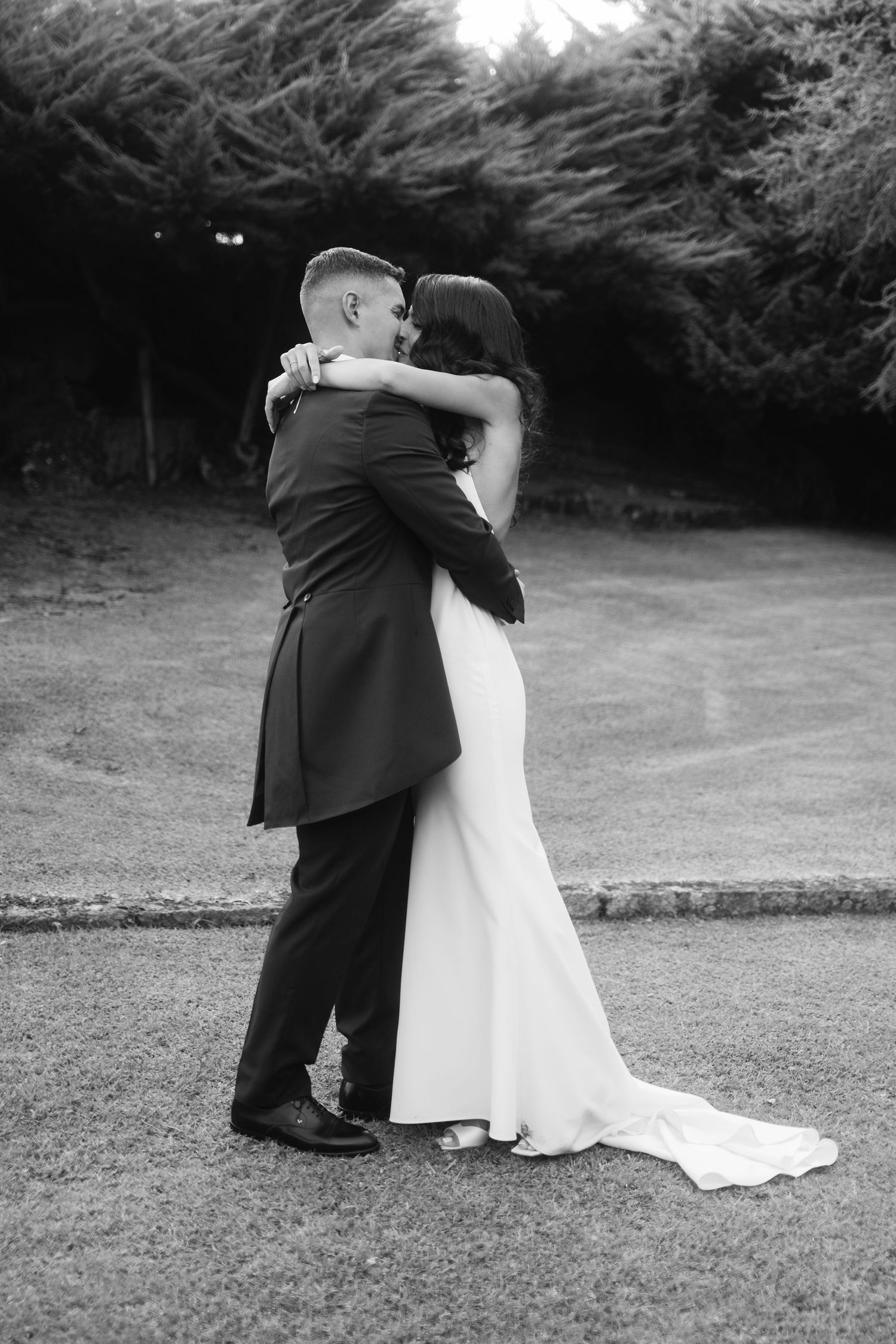 A sequence of black and white wedding photos showing a couple embracing on a grassy lawn.