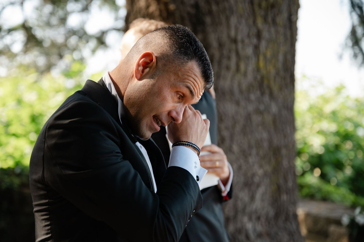 A couple in formal wedding attire embraces and shares an intimate moment in a garden setting.