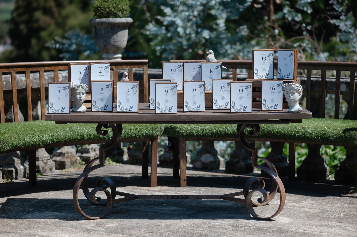 Panoramic collage of an outdoor art gallery display with framed photographs mounted on wooden easels in a garden setting.