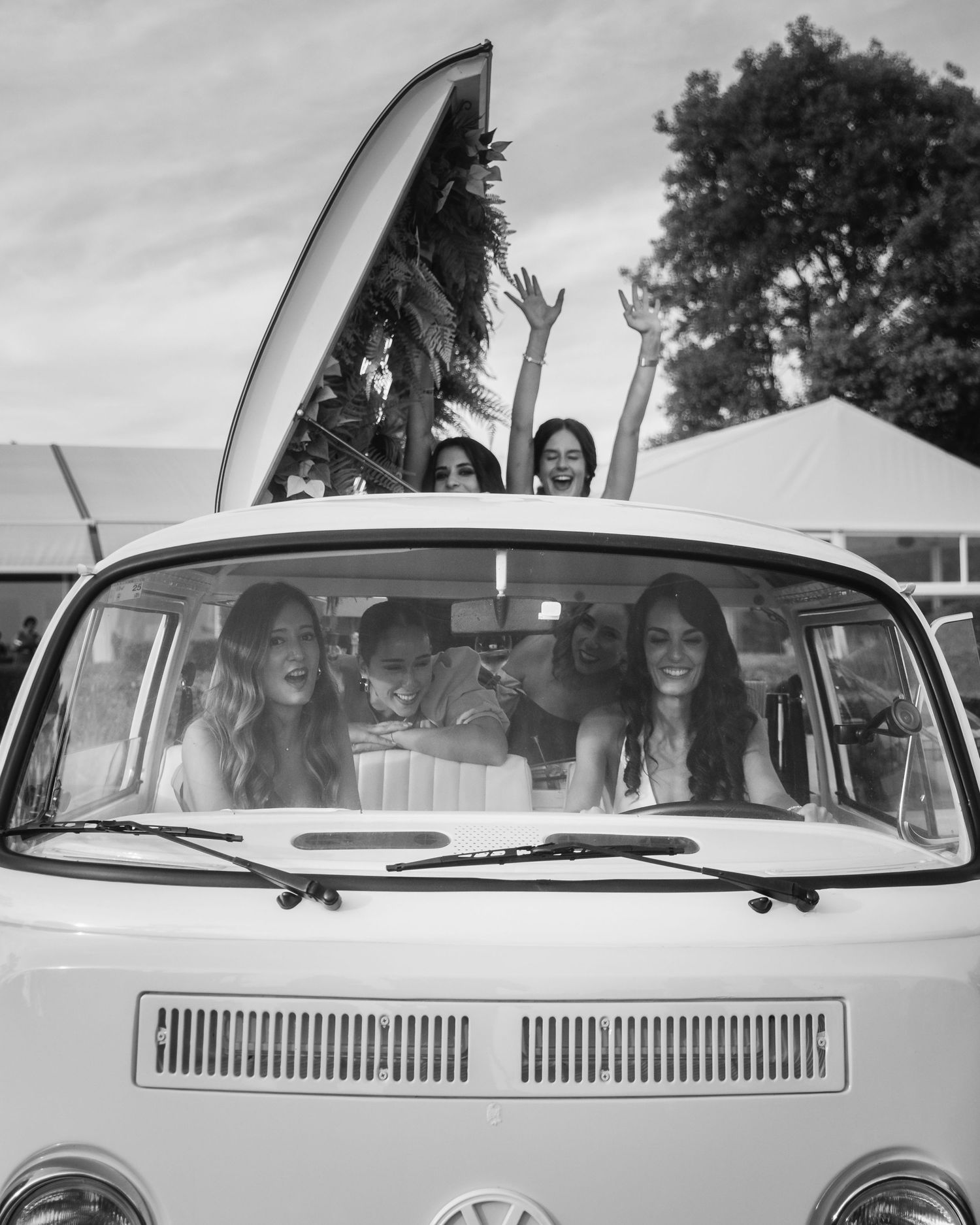 A classic white Volkswagen van with people visible through the windows, captured in black and white photography.