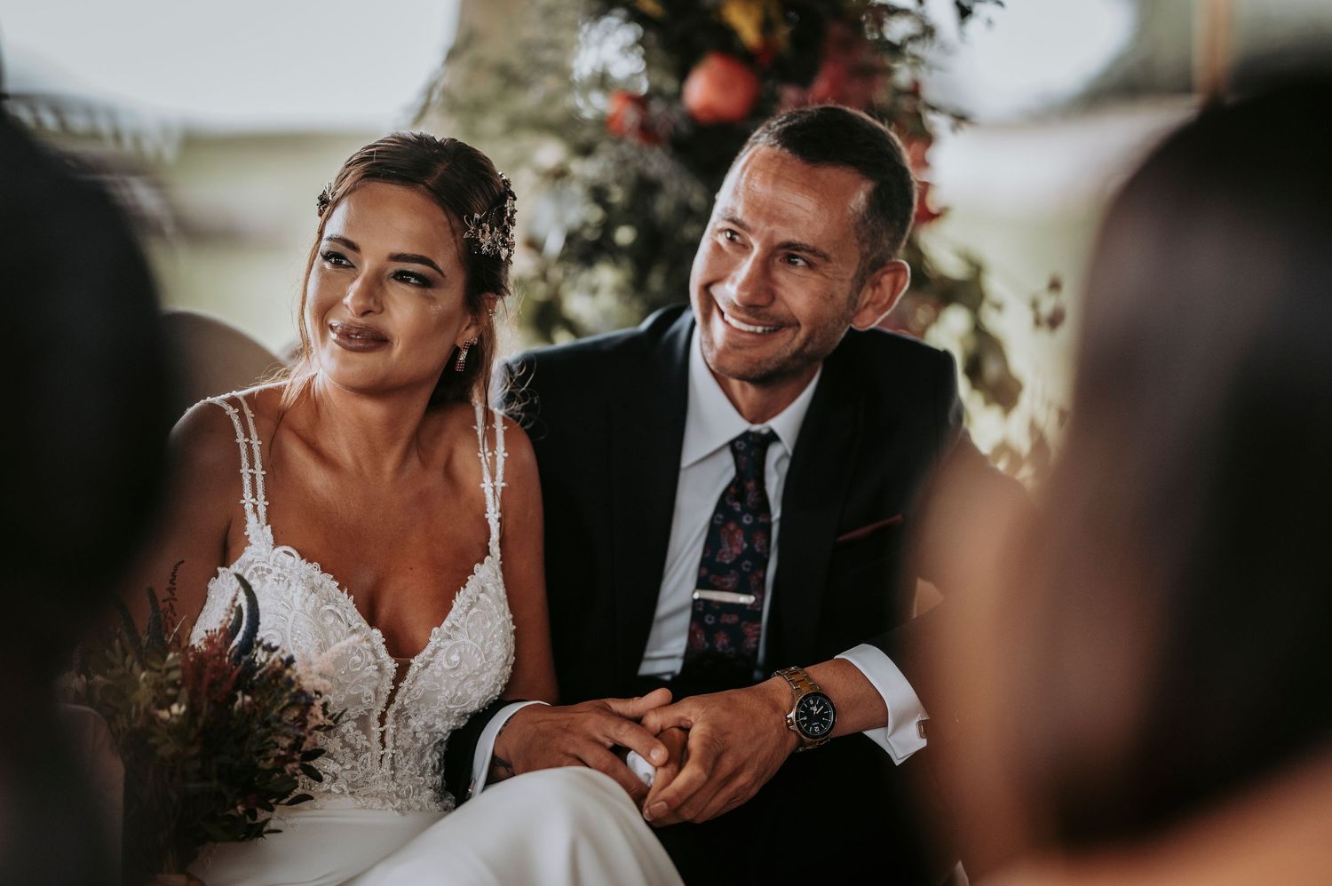 Close-up wedding photography capturing intimate moments with autumn floral arrangements in background.
