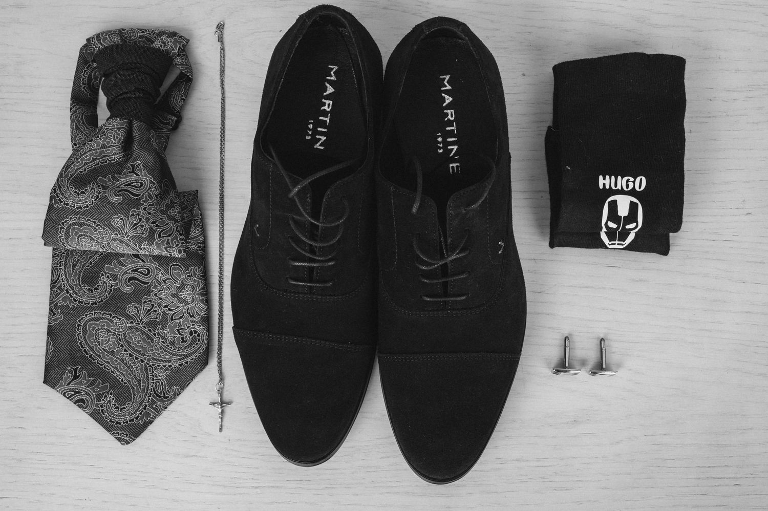 A collection of men's formal accessories including black shoes, ties, and gloves arranged on a light gray surface.