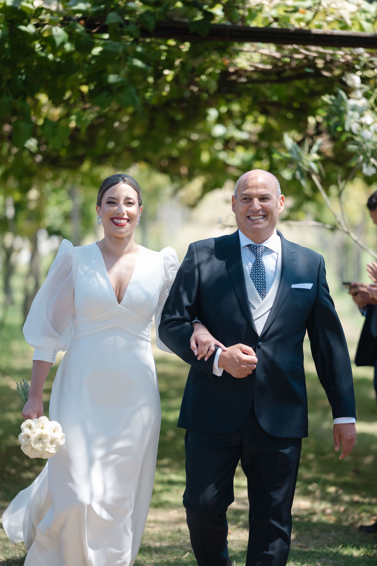 A couple walking and laughing together during an outdoor wedding celebration.