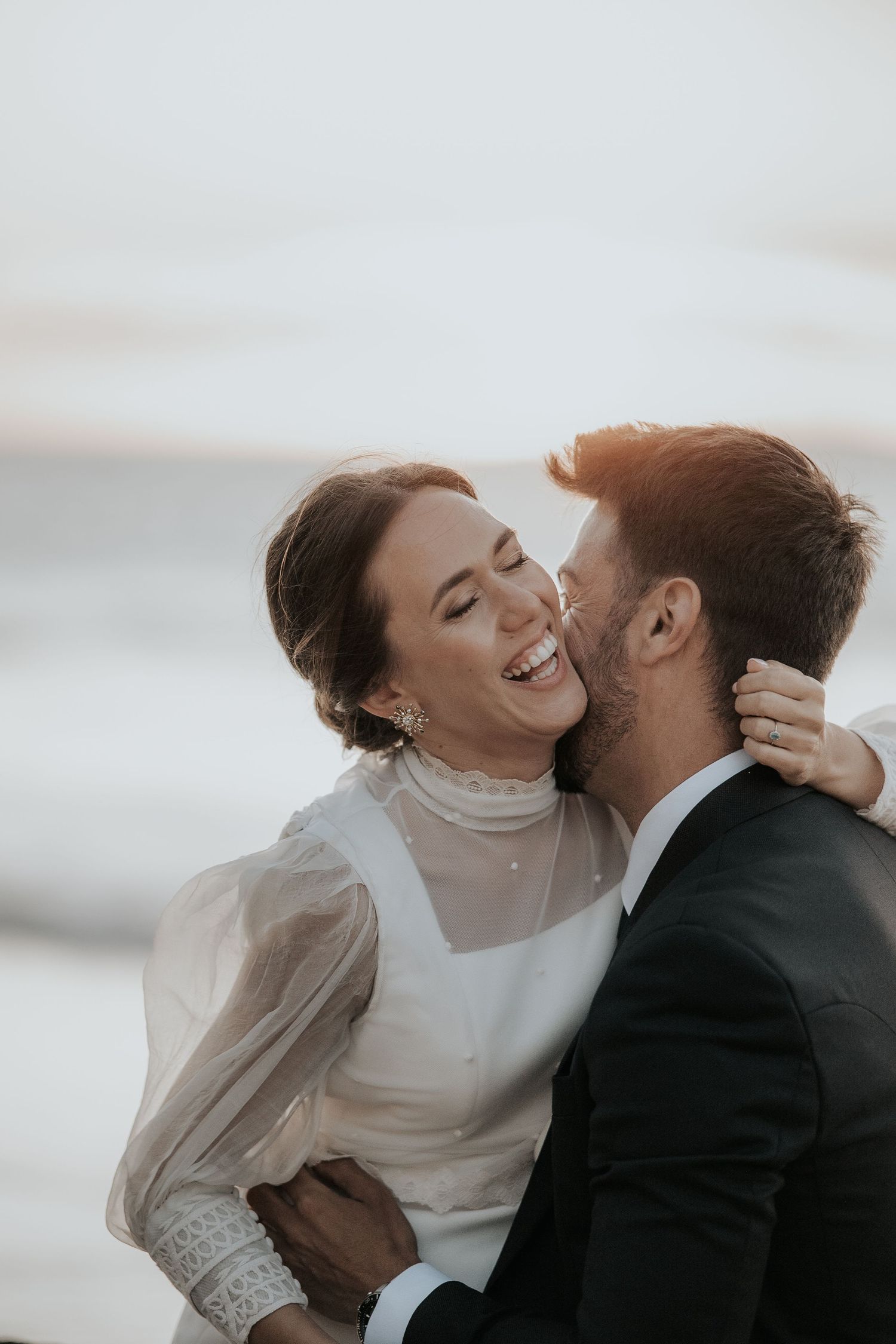 Joyful wedding moment captured with natural light as couple shares laughter and embrace.