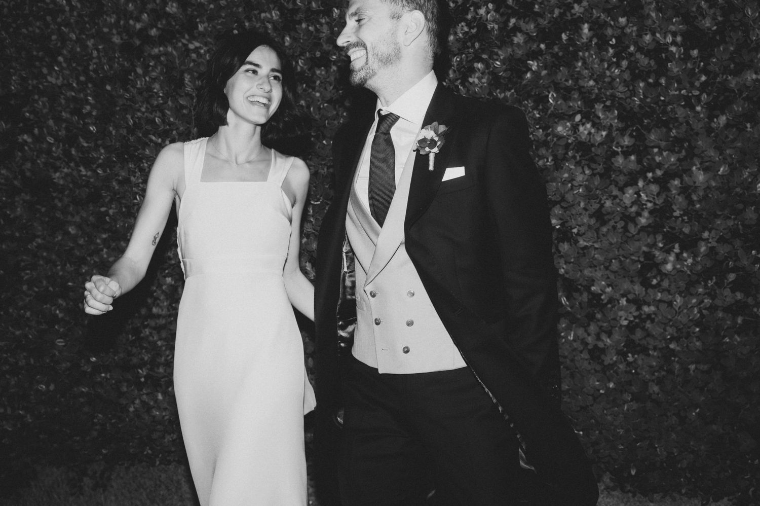 Monochrome wedding photograph showing a couple dancing and celebrating against a natural backdrop.
