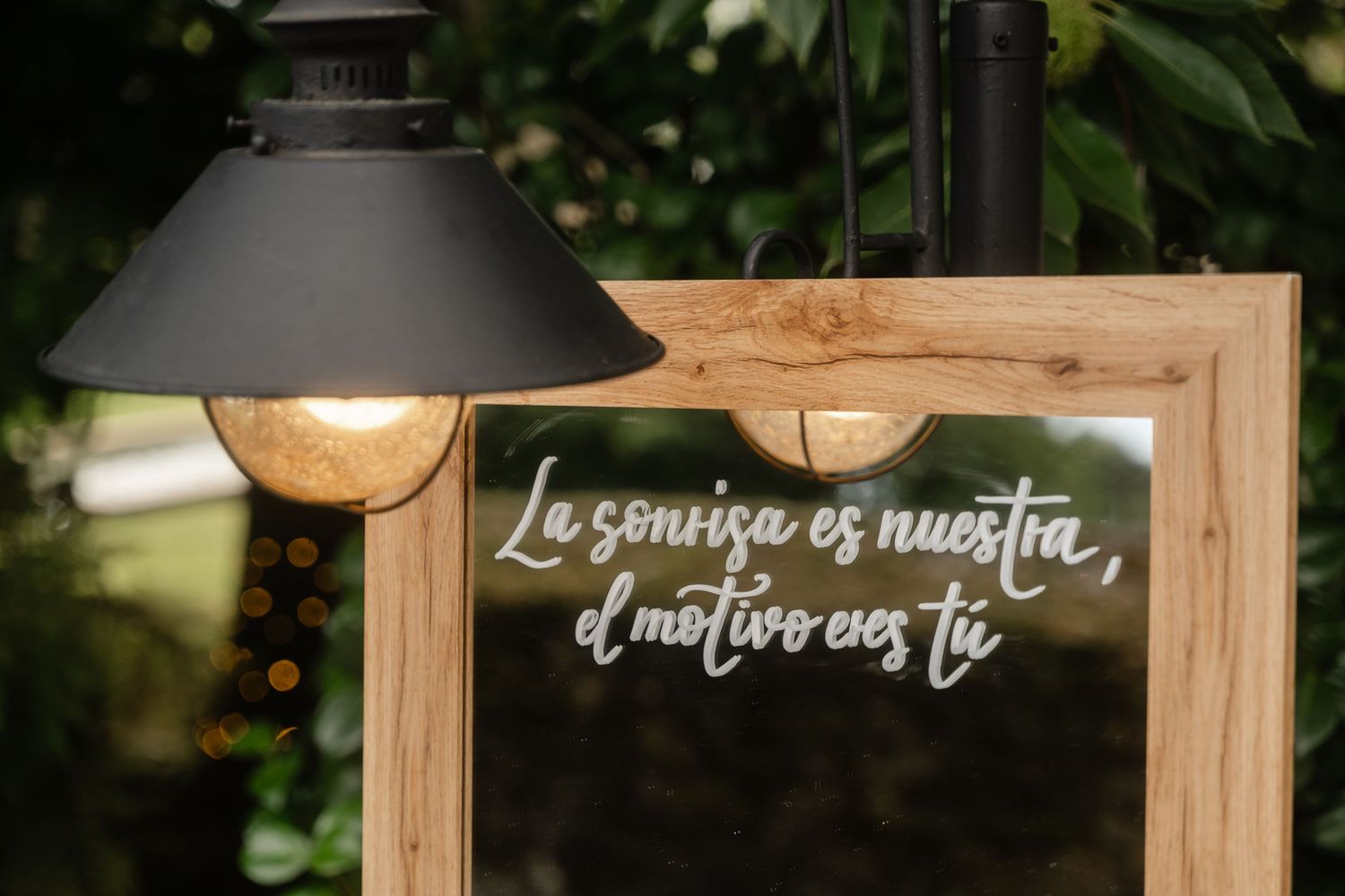 Wooden framed wedding signage with romantic text displayed against a blurred outdoor background.