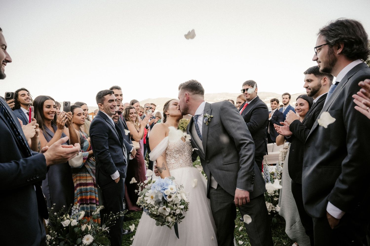 Wedding guests and party members gather outdoors for a celebratory group moment.