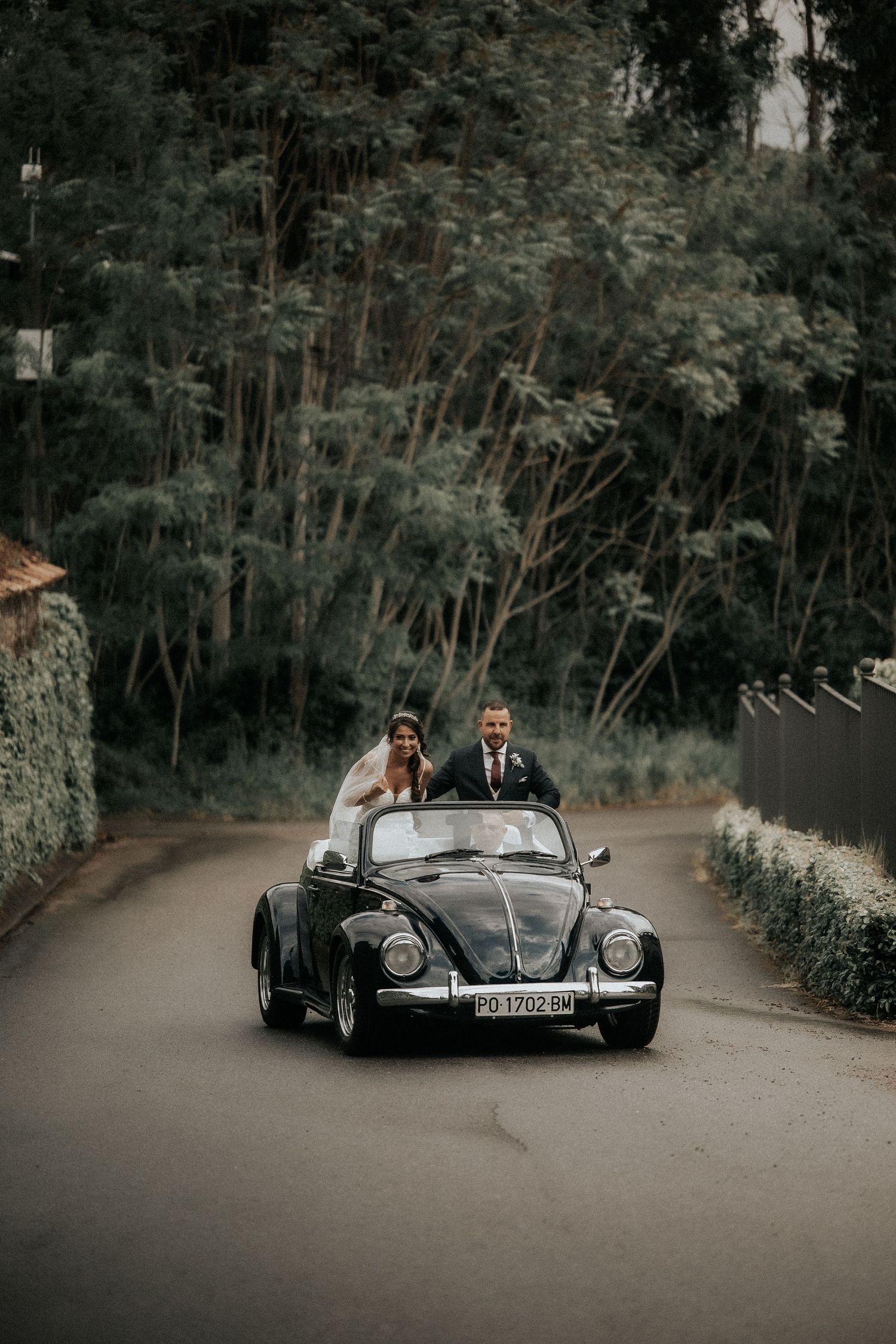 Classic black vintage Porsche convertible driving along a winding forest road.