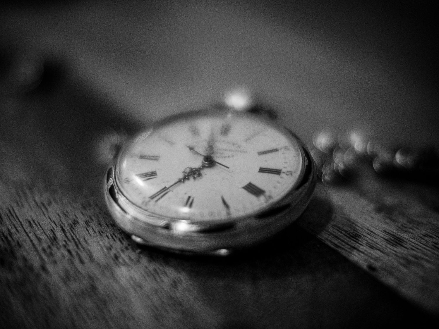 Close-up view of antique pocket watches in black and white with dramatic lighting and shallow depth of field.