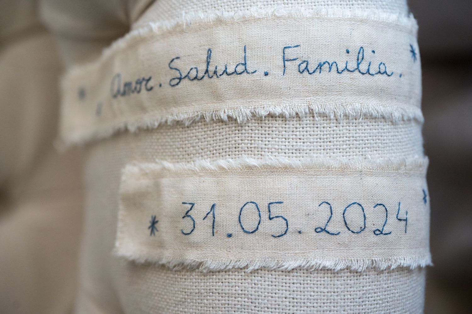 Handwritten text in blue ink on white fabric.