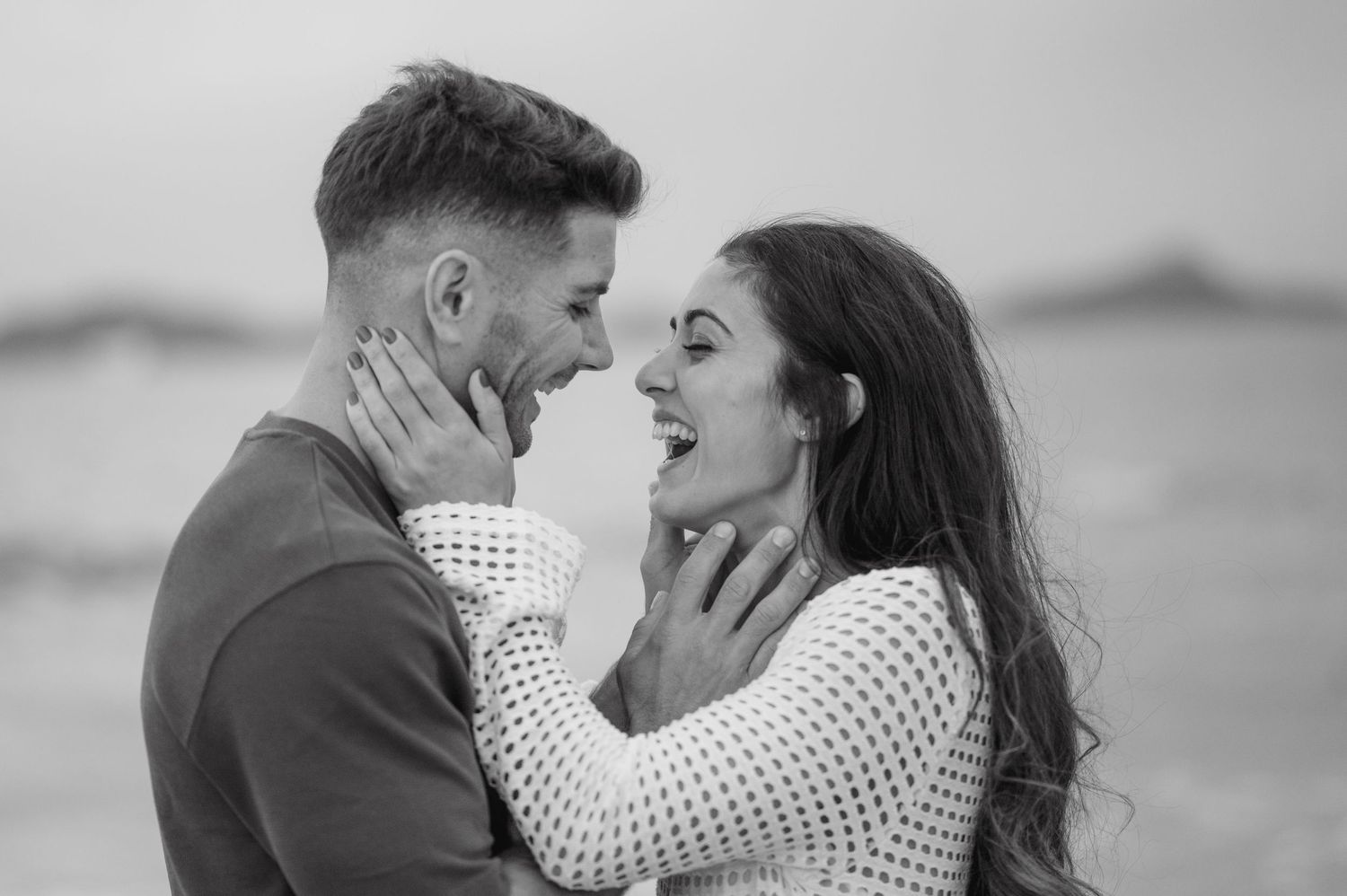A romantic black and white photo series shows a couple embracing and kissing on a beach.