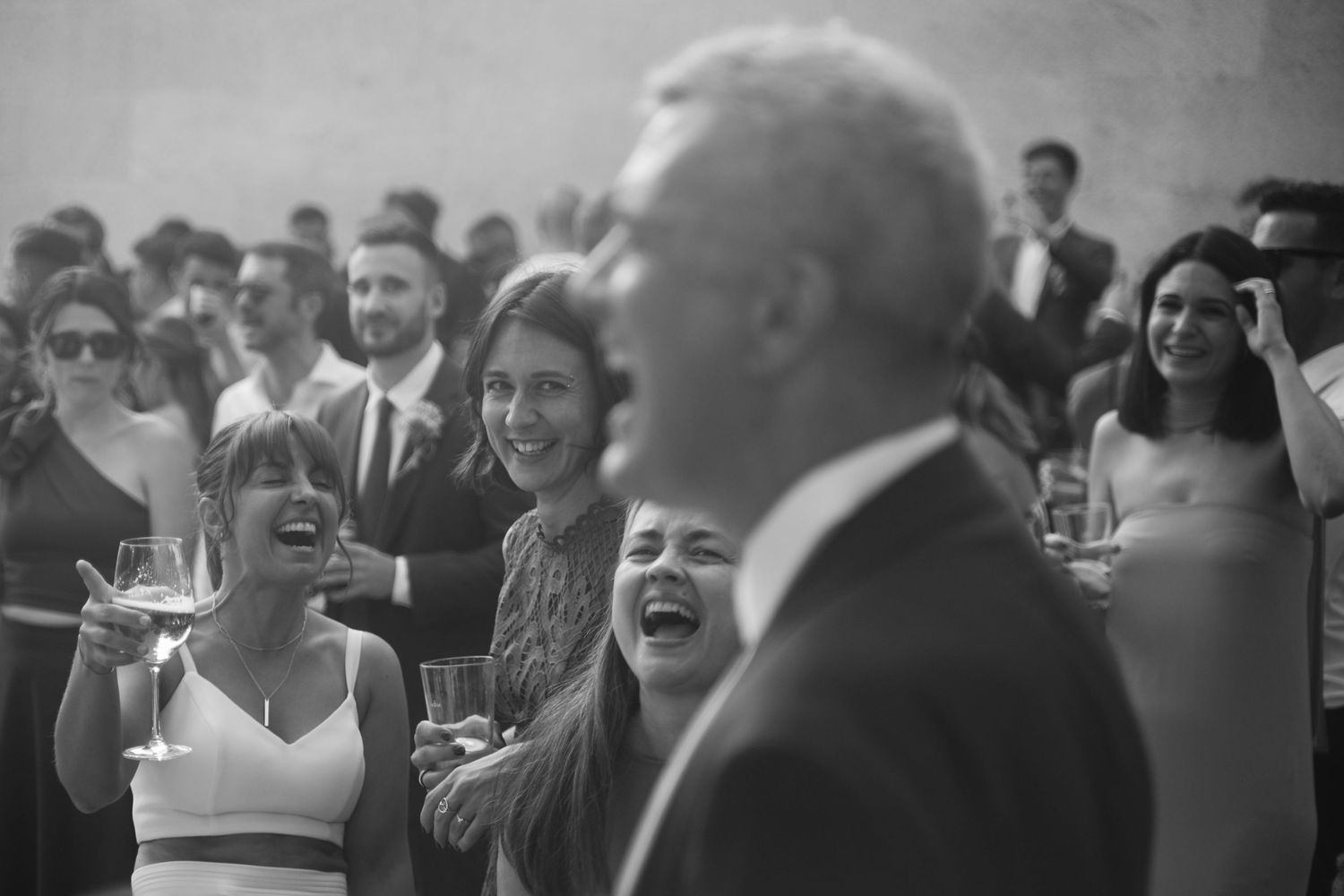 Black and white candid photo of wedding guests laughing and celebrating.