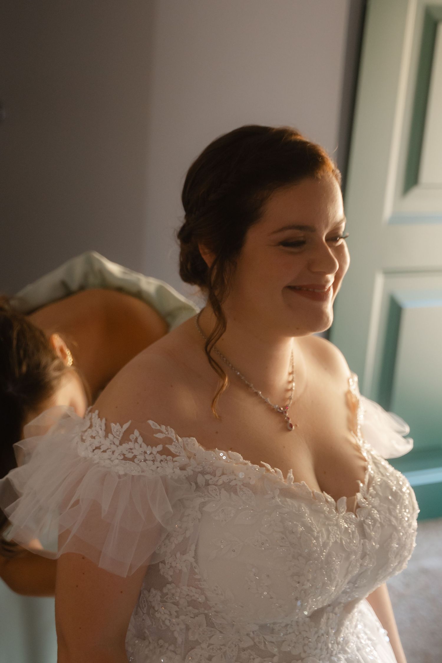 Elegant white lace wedding dress with off-shoulder neckline shown in soft natural light.