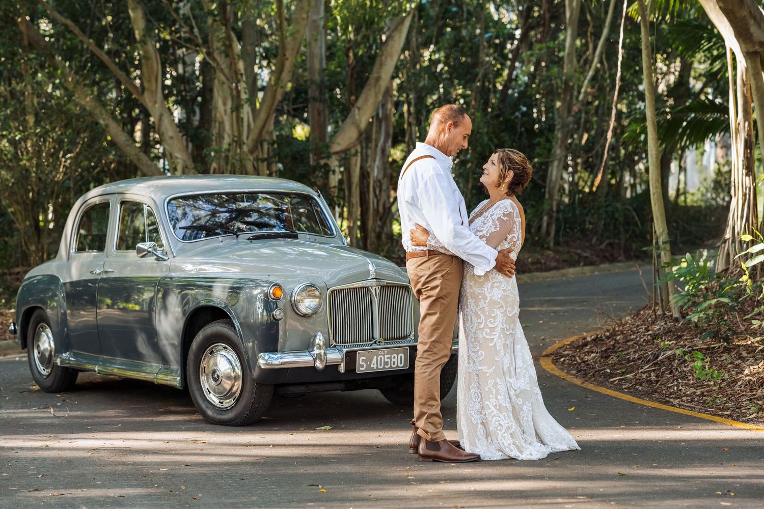 Bride and Groom posing with Classic Car