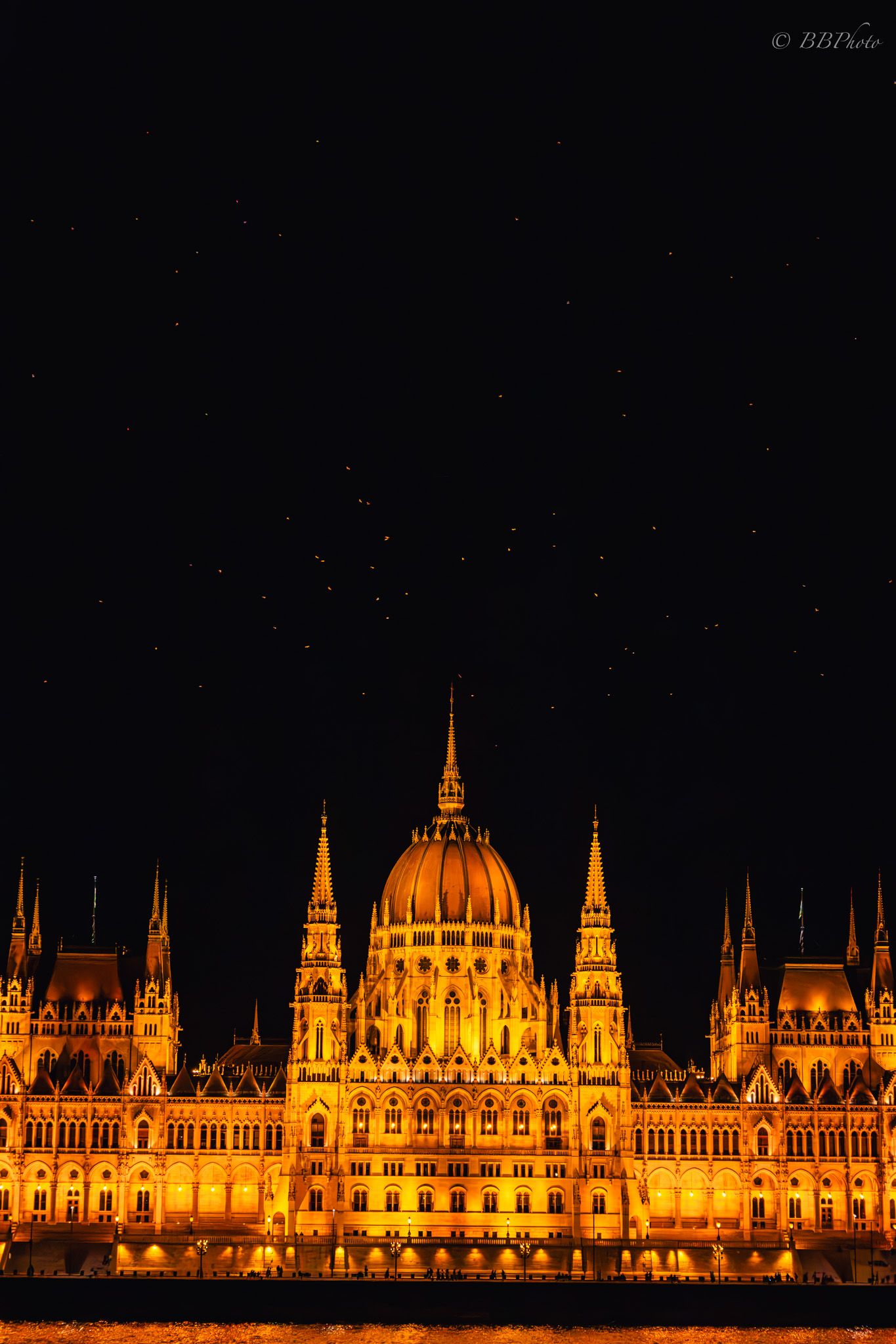 The Hungarian Parliament Building illuminated in golden light at night, reflecting on the Danube River under a starry sky.